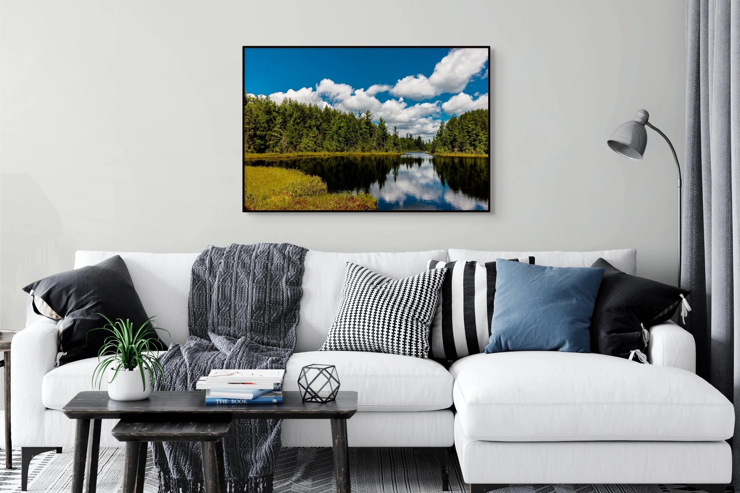 Living room scene with couch filled with pillows, and a photographic print of a northern Wisconsin lake in summer displayed on the wall