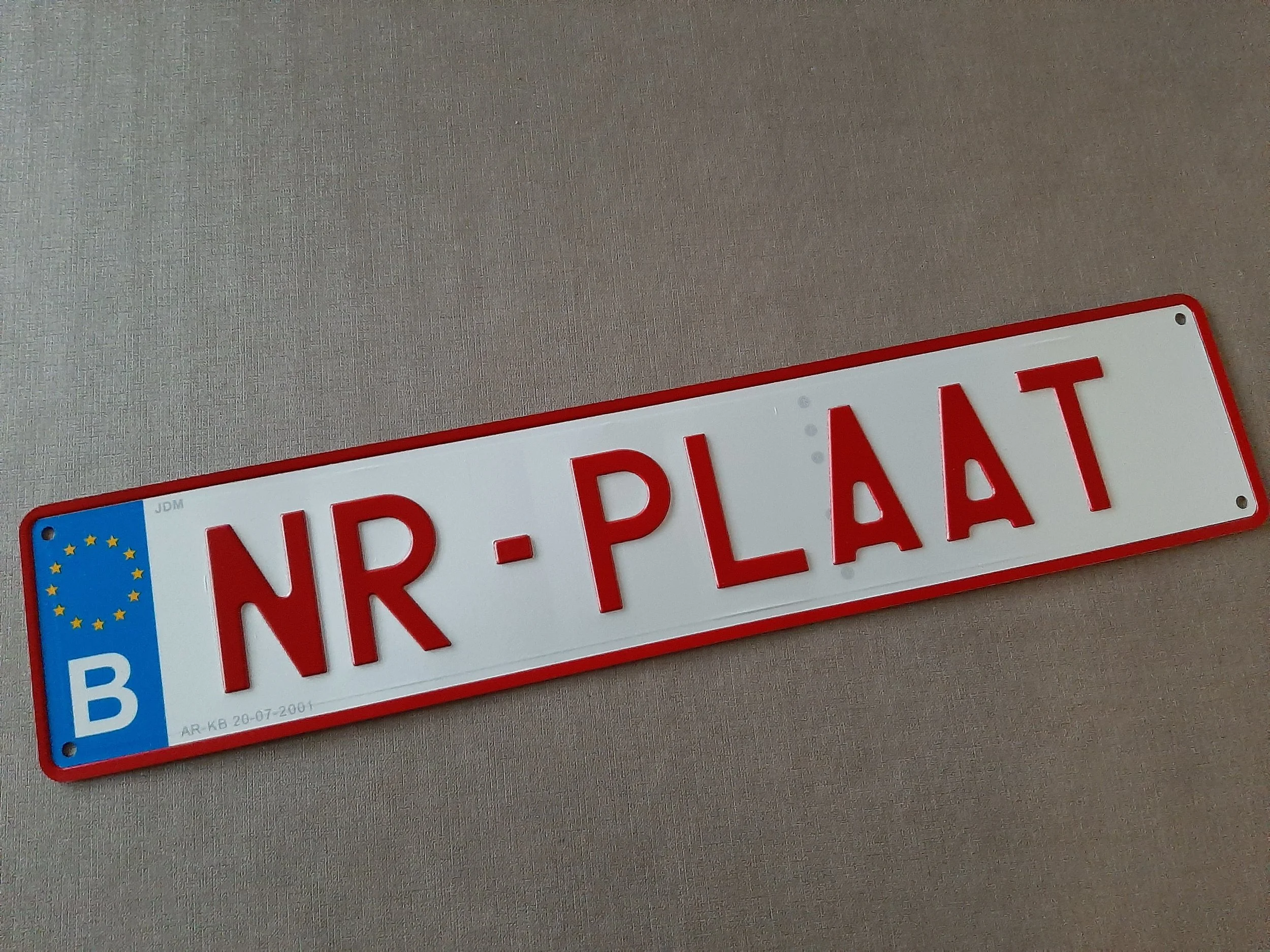 Belgische nummerplaat met "NR-PLAAT" op een grijze achtergrond.