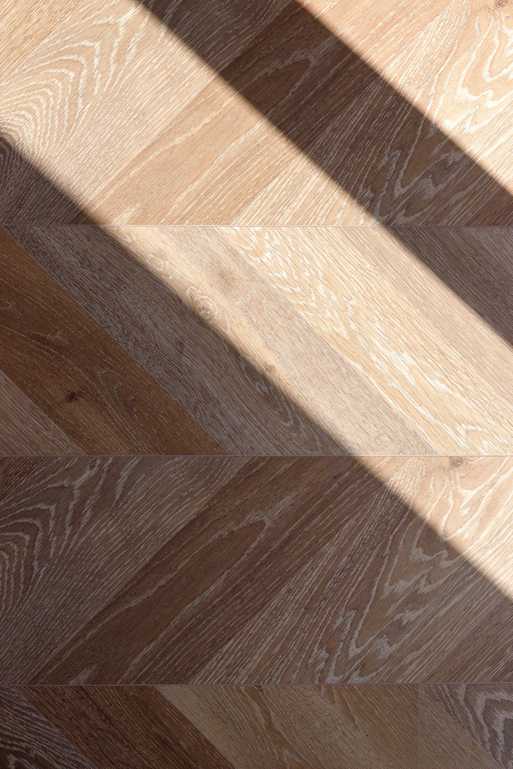 Chevron pattern wood flooring with sunlight shadows