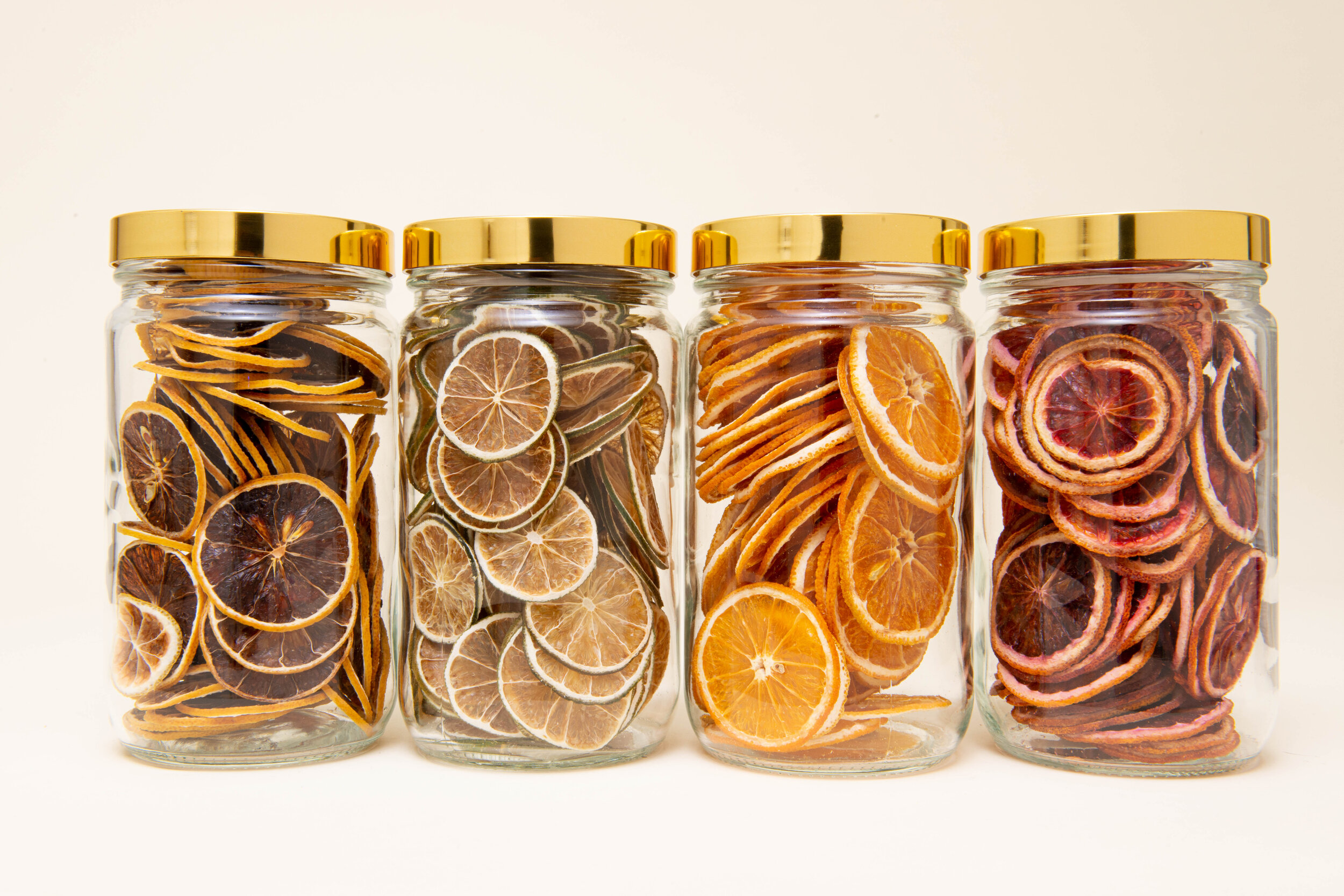 Large jar set containing dehydrated limes, dehydrated lemons, dehydrated oranges, and dehydrated blood oranges for cocktails