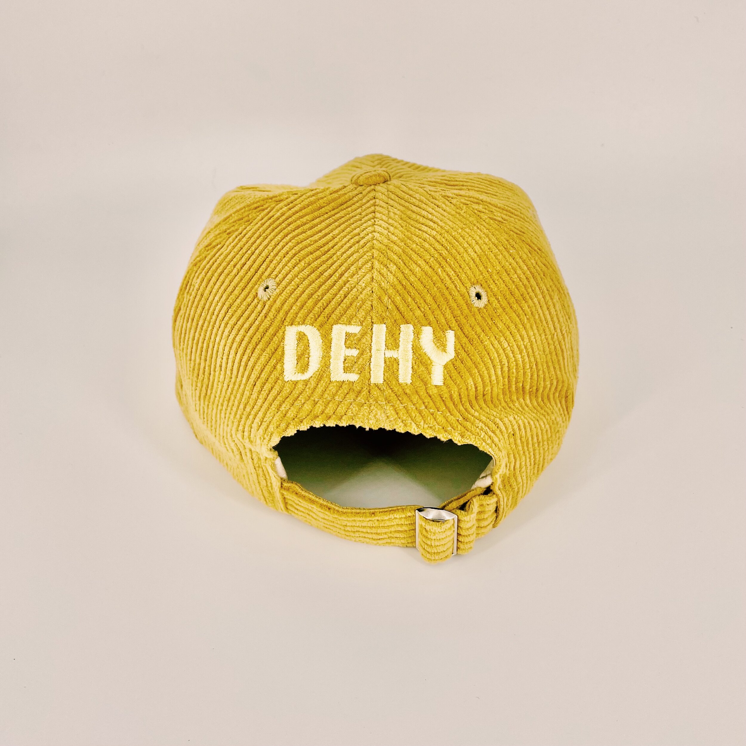 Back-facing six panel, unstructured gold corduroy hat featuring the DEHY Sphinx logo. Lower profile with an adjustable metal hoop