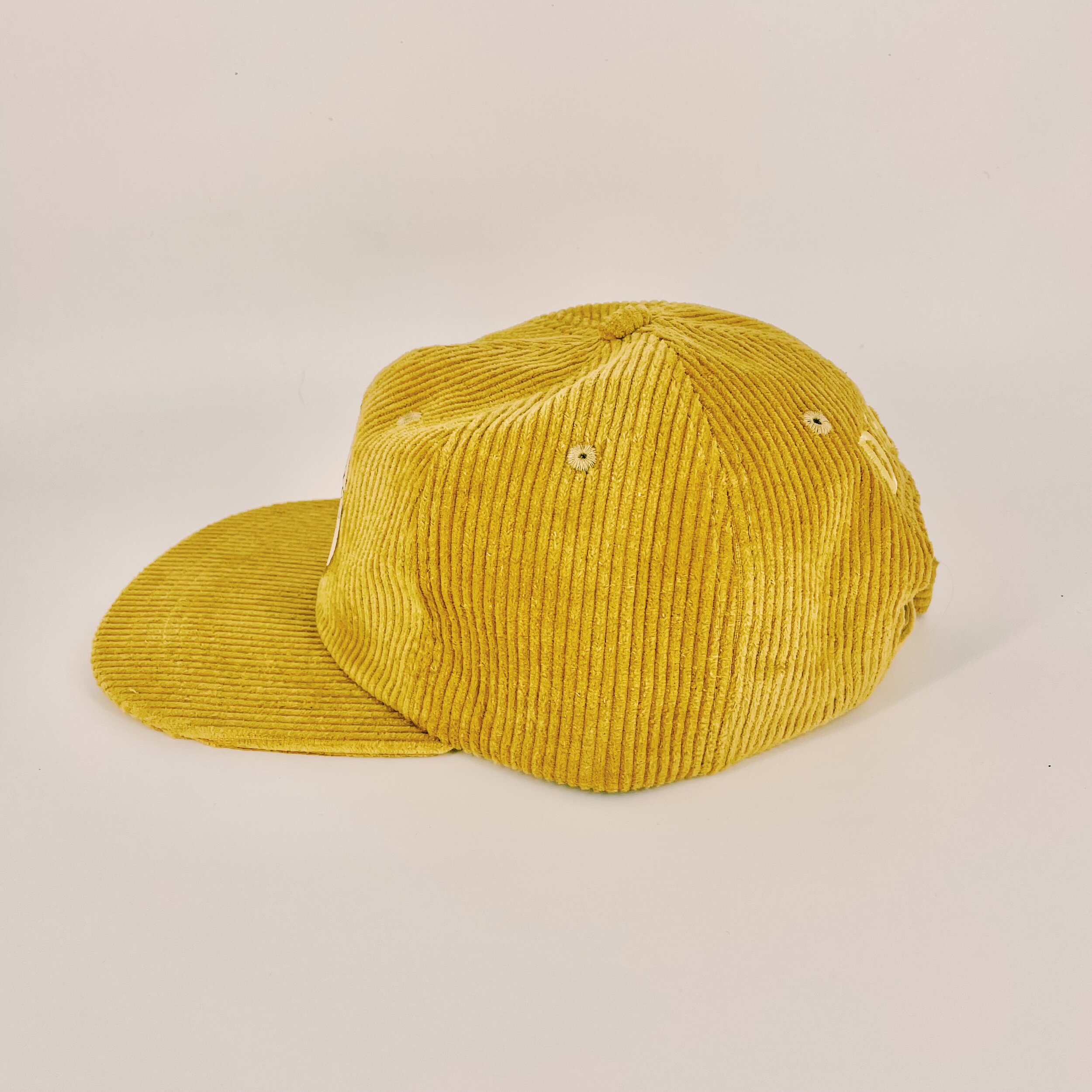 side-facing Six panel, unstructured gold corduroy hat featuring the DEHY Sphinx logo. Lower profile with an adjustable metal hoop
