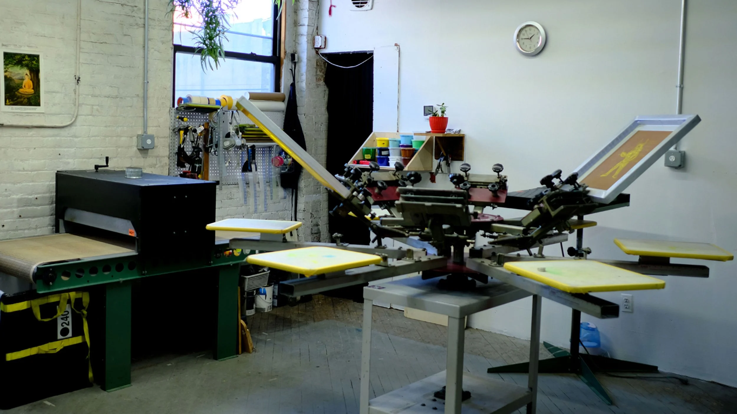 A medical or surgical examination table in a clinical setting with yellow and black caution tags. The room has white brick walls, a window with natural light, and various shelves and tools for medical or veterinary use.
