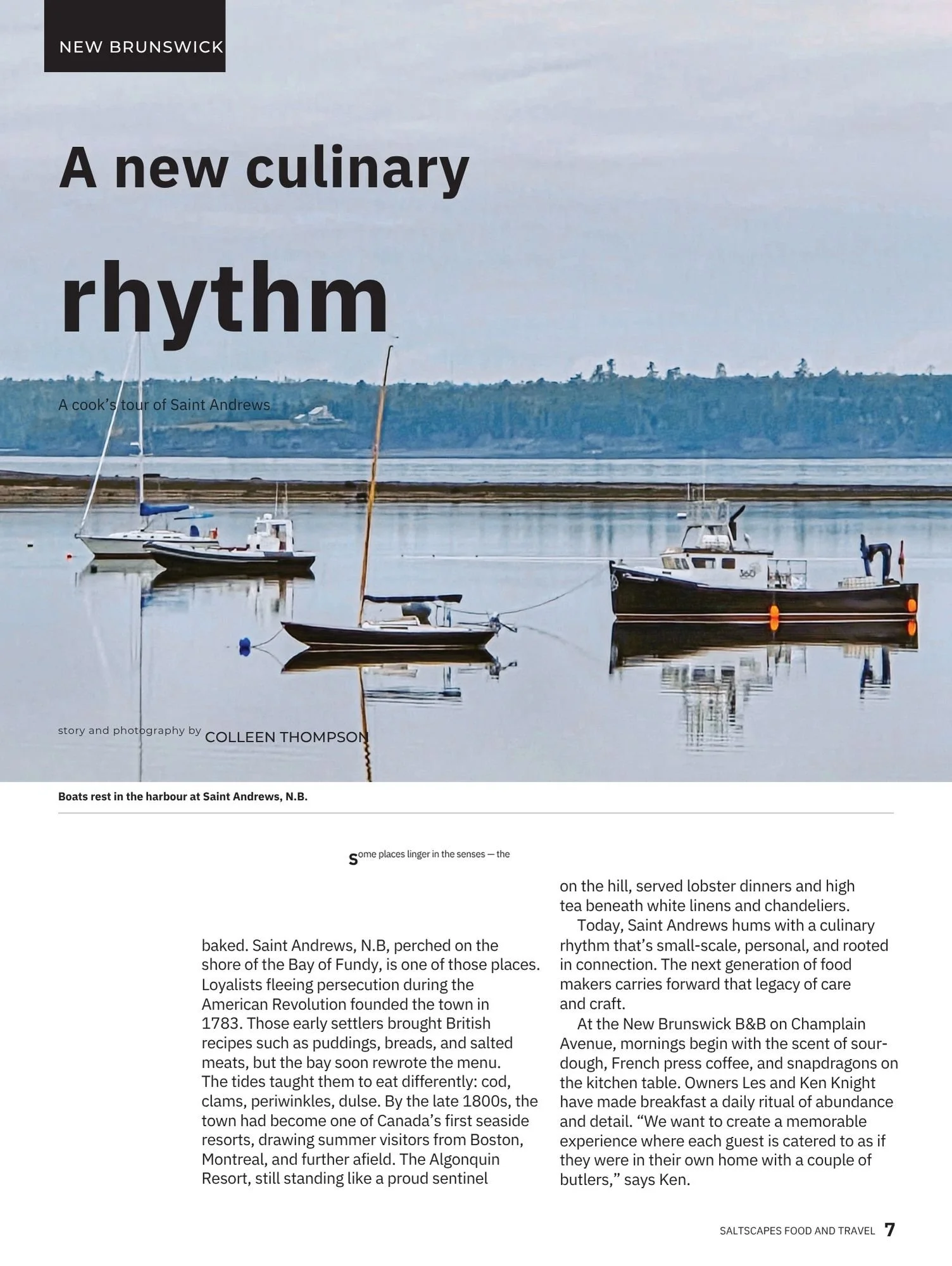 Photo of sailboats and motorboats anchored in a harbor at Saint Andrews, New Brunswick, with calm water reflecting the boats and a distant shoreline with trees and buildings under an overcast sky.