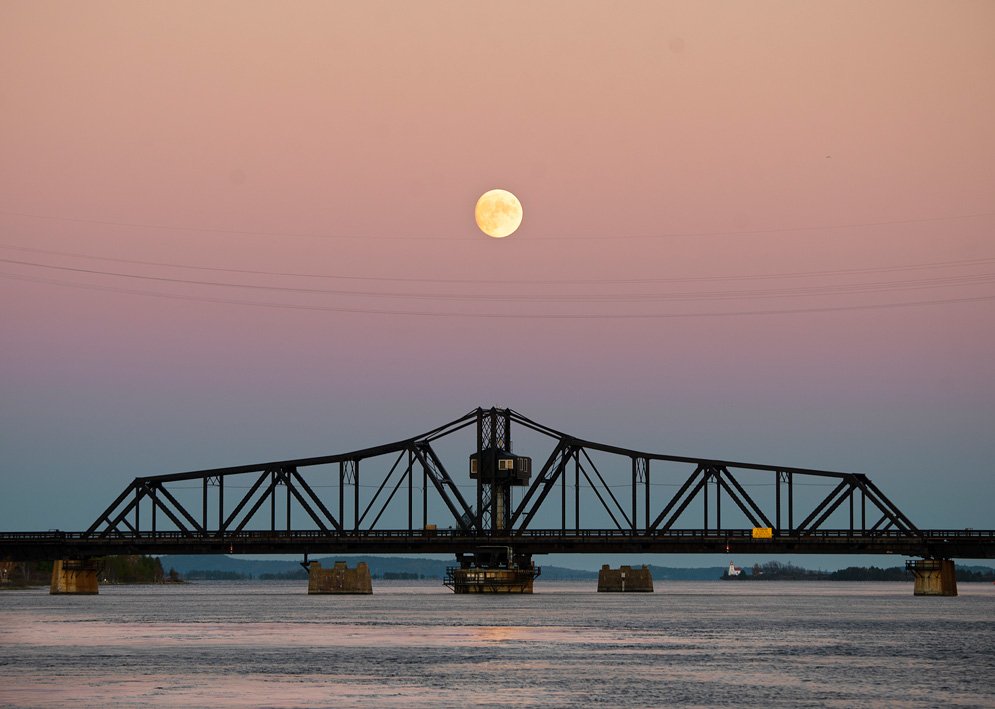 Little Current swing bridge at sunset with moon in the middle background