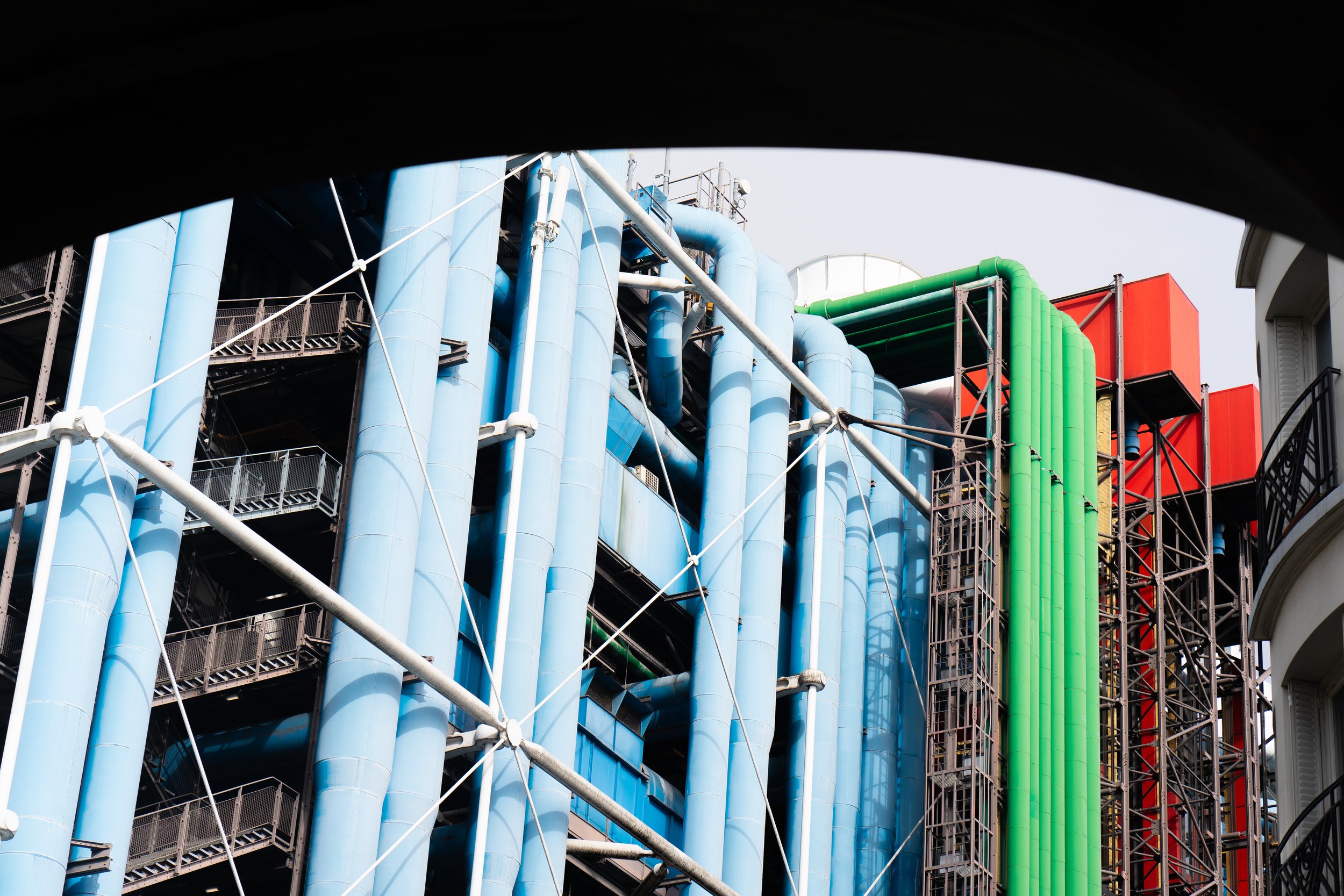 Close-up of a modern building facade with brightly colored vertical pipes and structural framework.