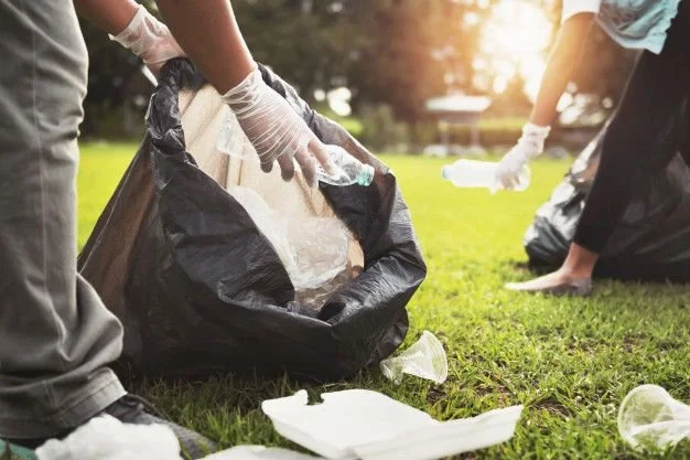 Mother and children keeping garbage plastic bottle into black bag at park in morning light _ Premium Photo.jpeg