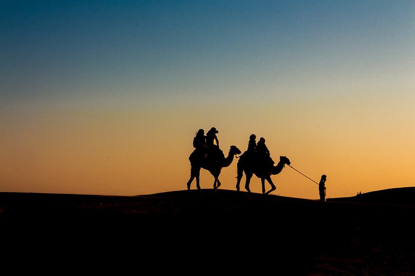 Imágen de comerciantes árabes por el desierto con camello.