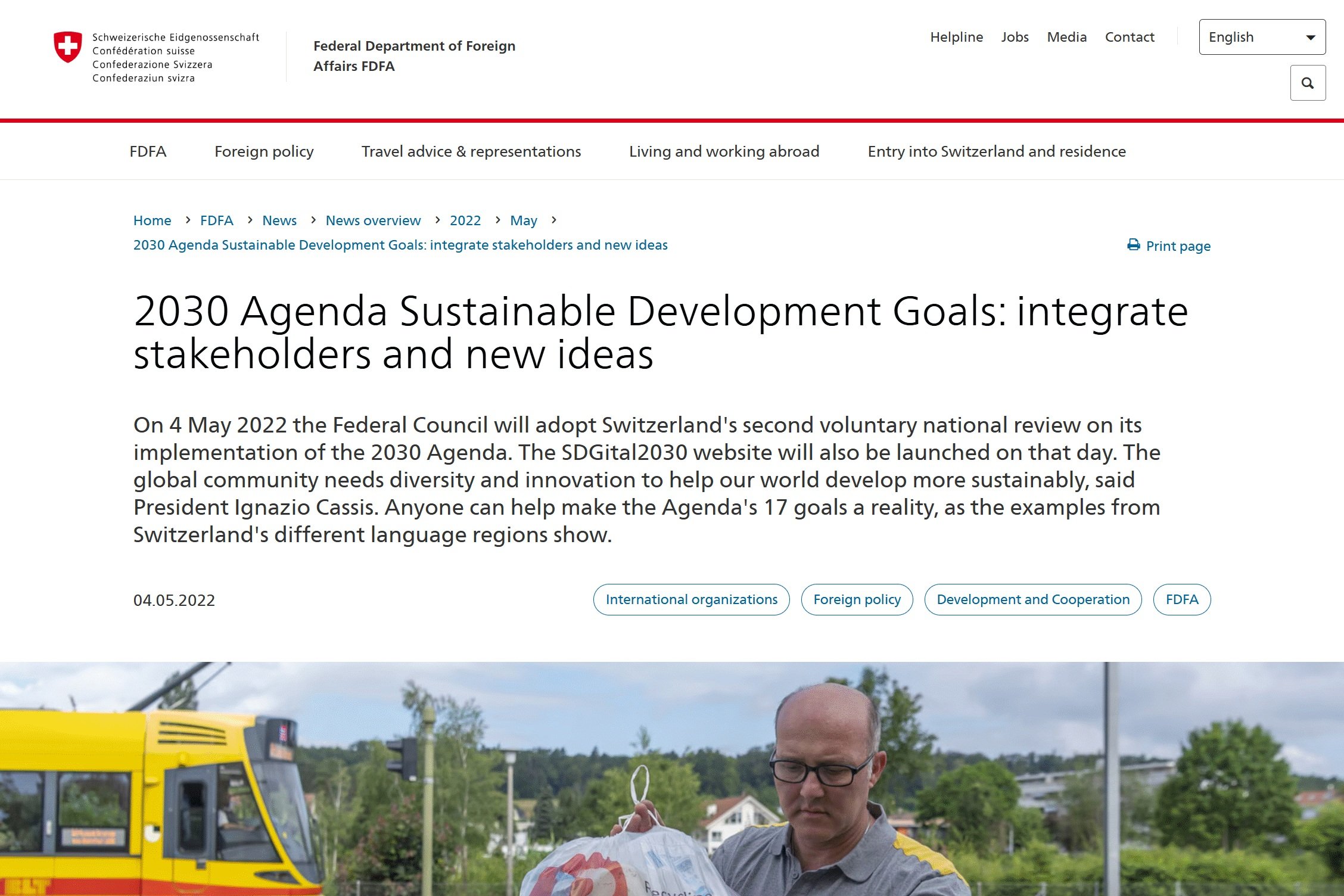 Switzerland's Federal Department of Foreign Affairs webpage titled '2030 Agenda Sustainable Development Goals: integrate stakeholders and new ideas' with a partially visible yellow bus and a man holding a plastic bag in a green outdoor setting.