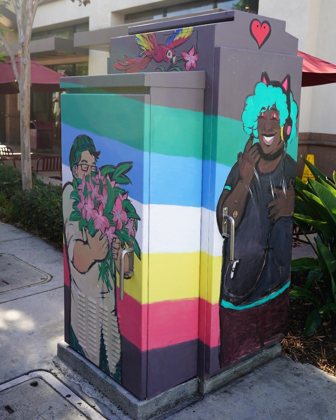 Our third stop for our Beyond the Box Biking Tour is &ldquo;We Are Here&rdquo; by Milton-Scott Kobuta. Kobuta&rsquo;s work features a disability pride flag in the background and three individuals with disabilities. The title &ldquo;We Are Here&rdquo;