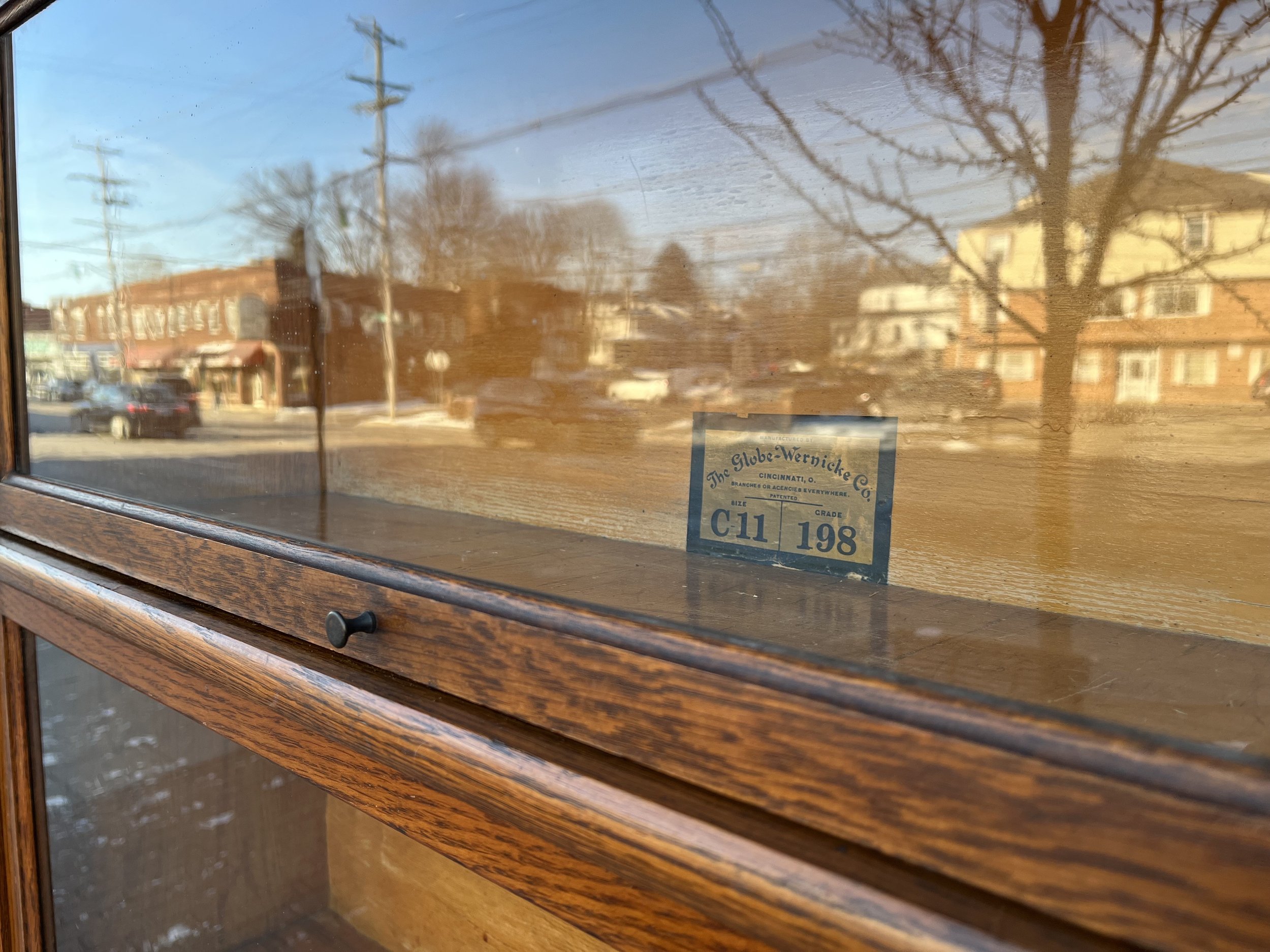 Detailed shot of the original Globe Wernicke label and hardware on the antique barrister bookcase, emphasizing its authenticity and historical significance