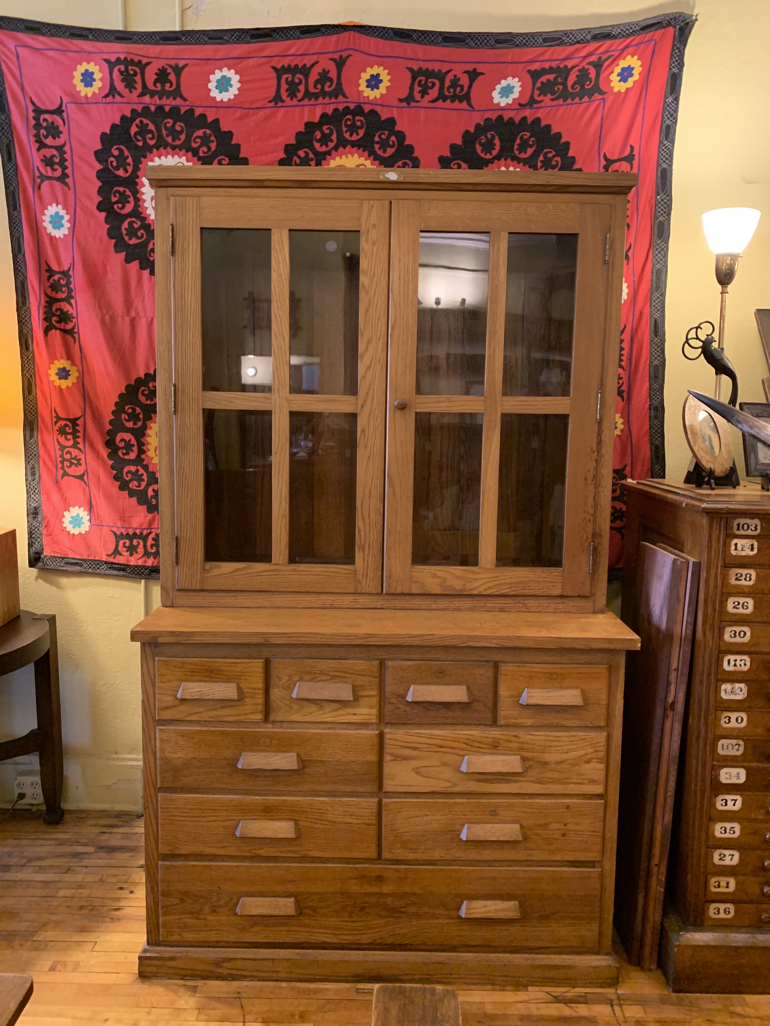 Antique E.H. Sheldon school cabinet with glass doors, solid oak construction, and nine drawers.