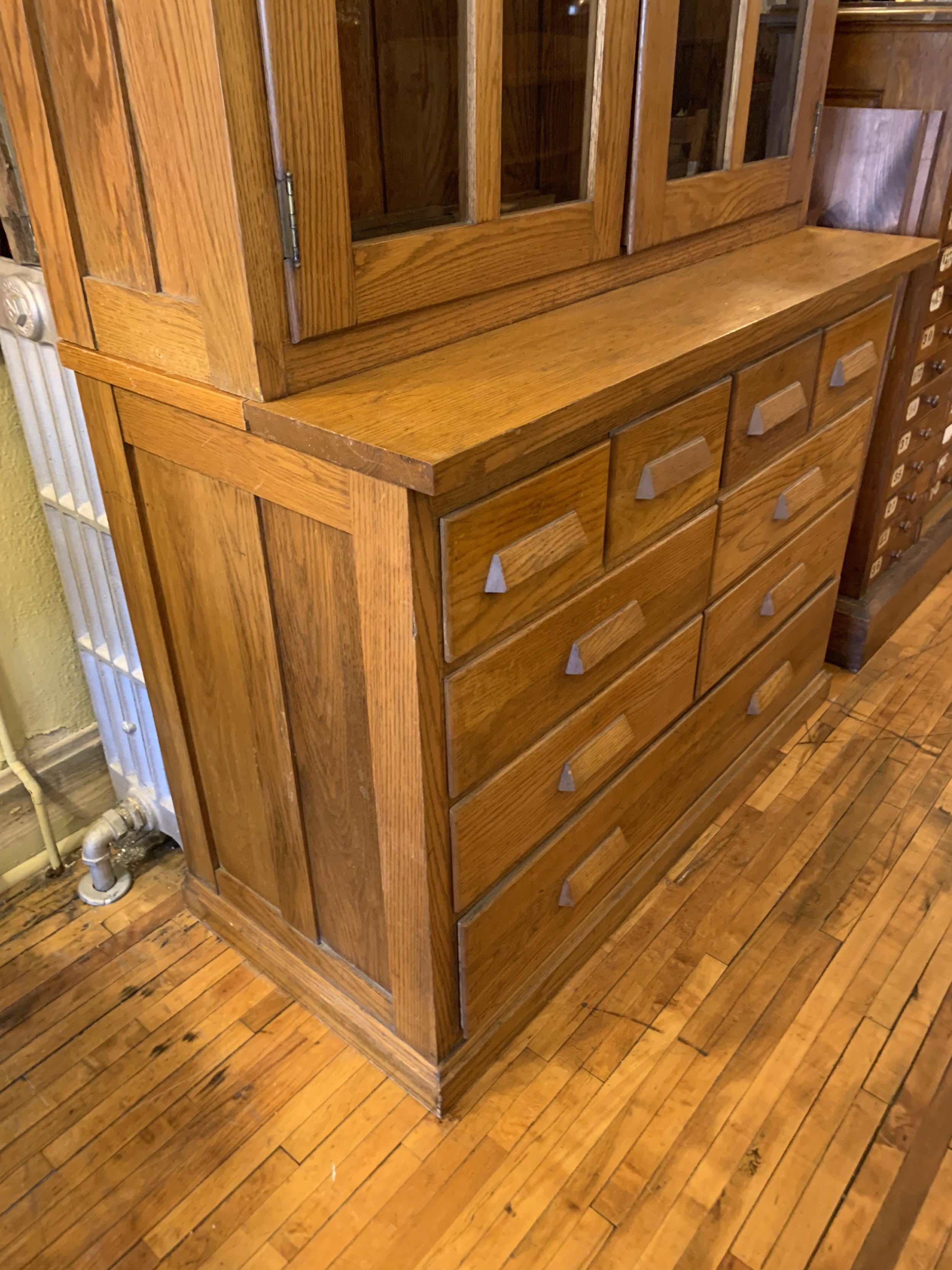 Close-up of the lower section of an antique E.H. Sheldon oak cabinet showcasing nine drawers with original pulls