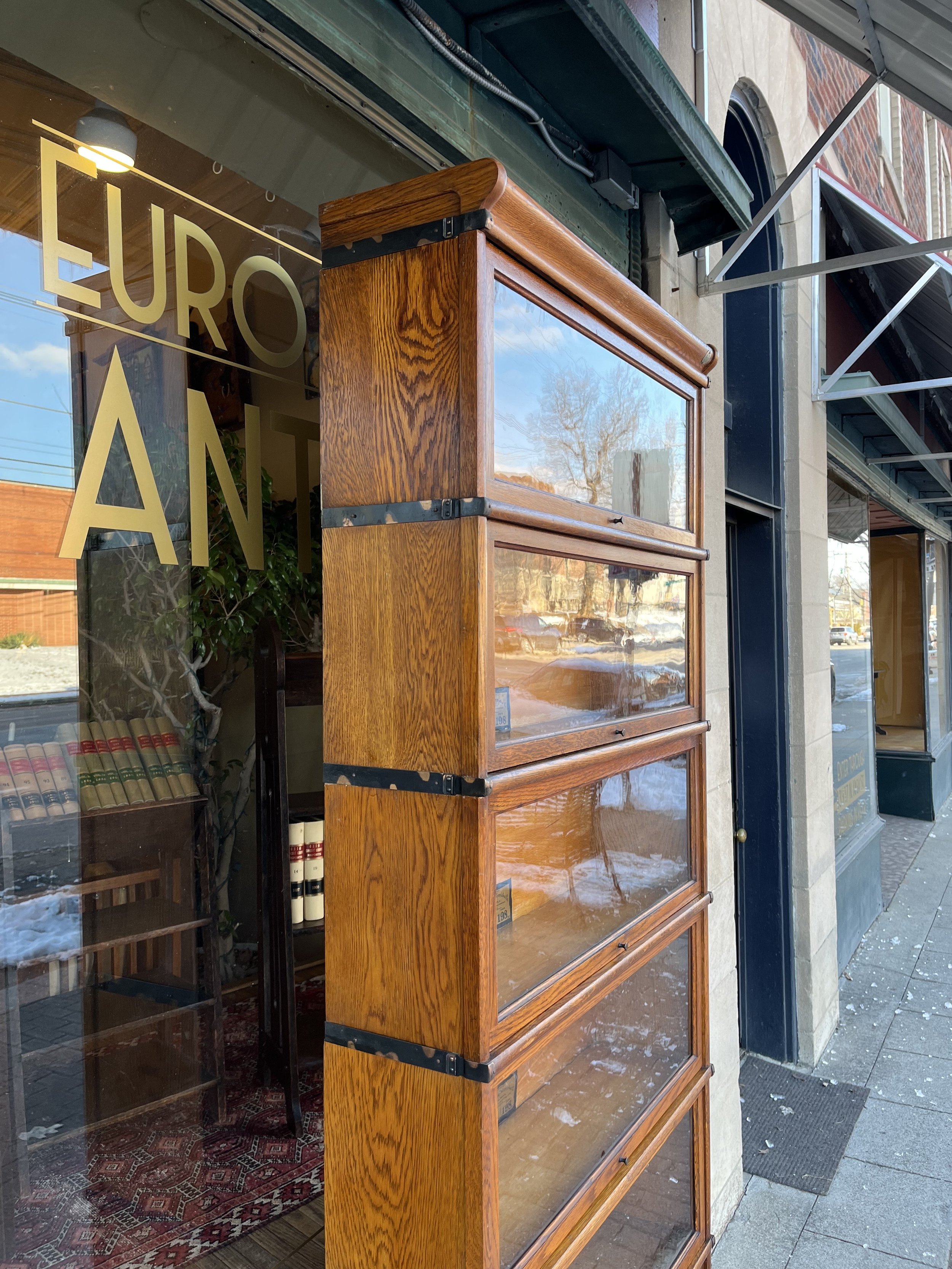 Close-up of Globe Wernicke barrister bookcase showcasing retractable glass doors, metal banding, and rich oak grain from early 20th-century craftsmanship