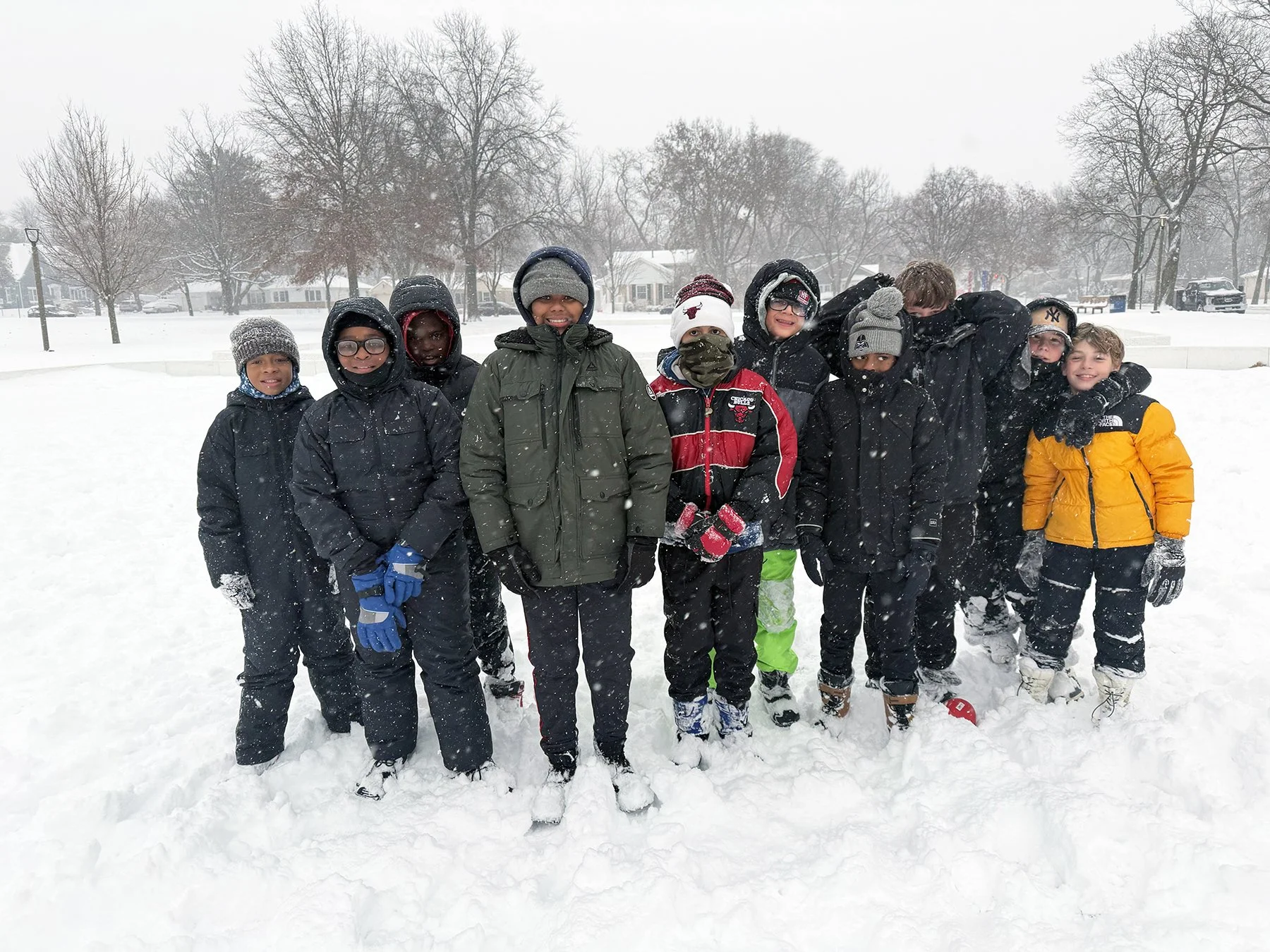 Group of bundled up boys gathered for a photo during a snowfall
