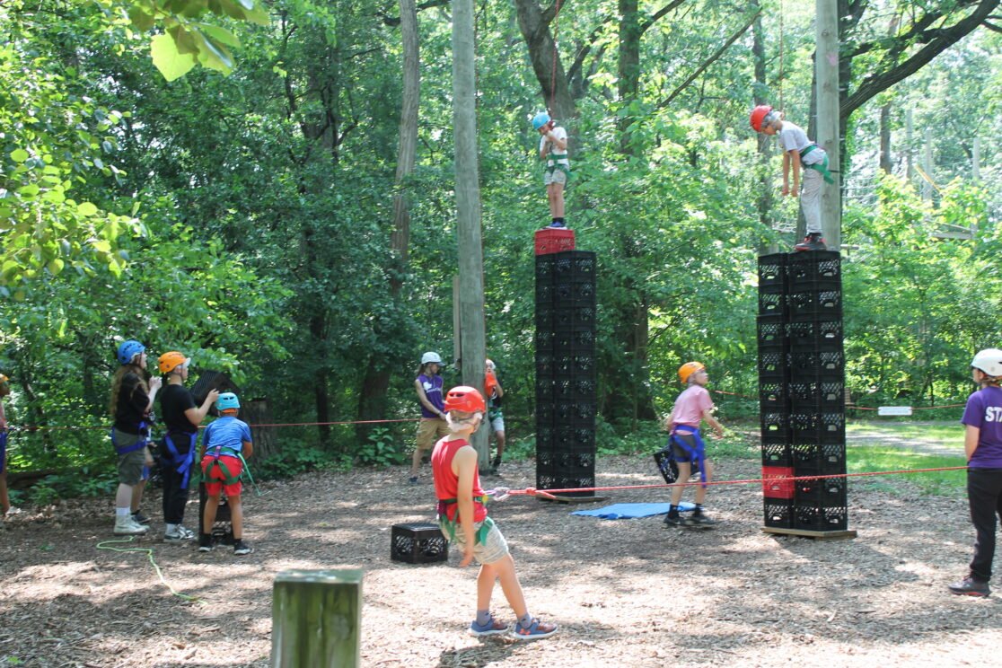People climb crates in the woods