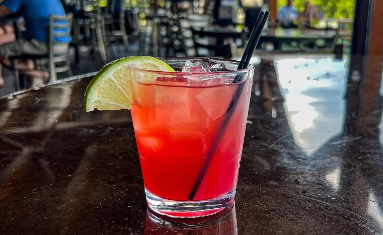 Royal Rum Runner cocktail from Royal Bliss with Coconut rum, spiced rum, sour mix, pineapple, cranberry, orange with a fresh lime garnish.