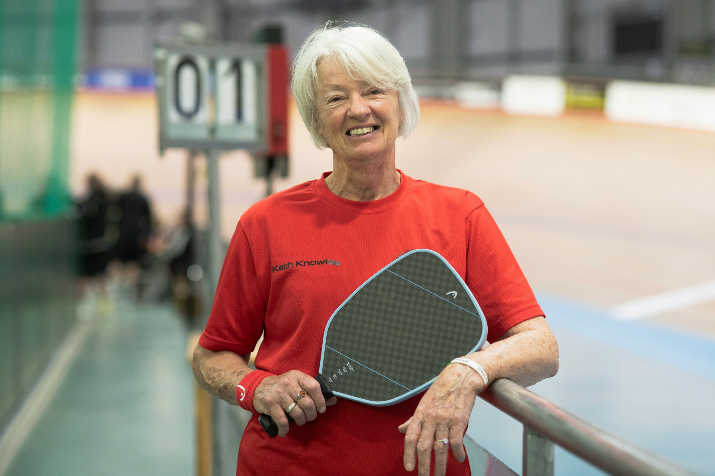 Person doing a seated forward bend stretch on a pink yoga mat while looking at a laptop.