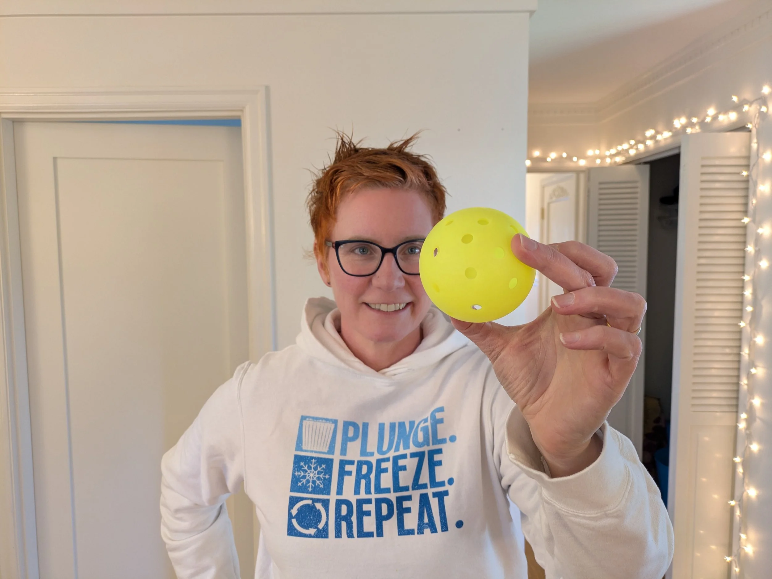 Person in workout attire standing on a Pilates reformer in a room with framed pictures and a mountain art piece on the wall.