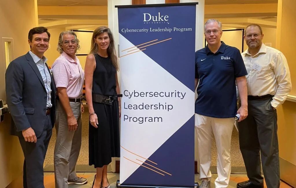 four male and one female faculty members grouped beside the banner for their cyber program