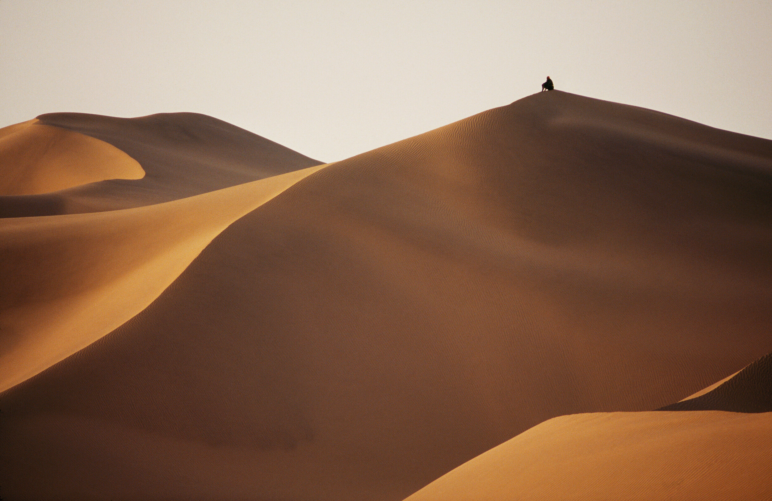  Esa Polte, one of the Uighur camel handlers climbs a giant dune near camp at the end of a day.  