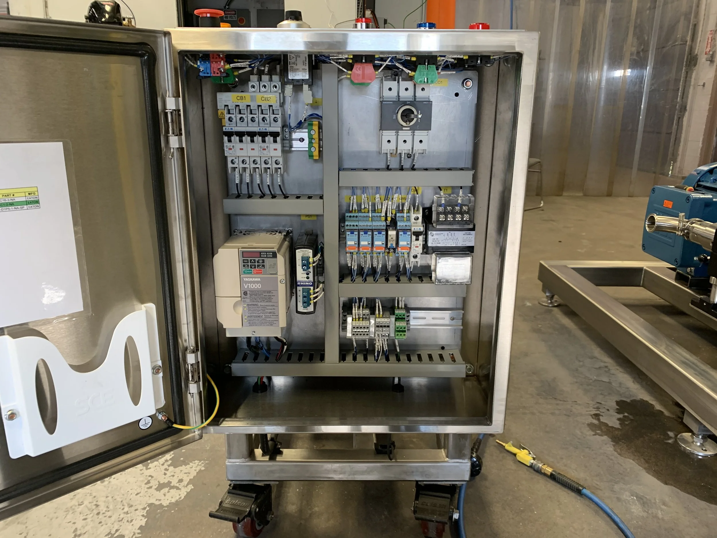 Open electrical control panel with various wiring, switches, relays, and circuit breakers inside a metallic enclosure.