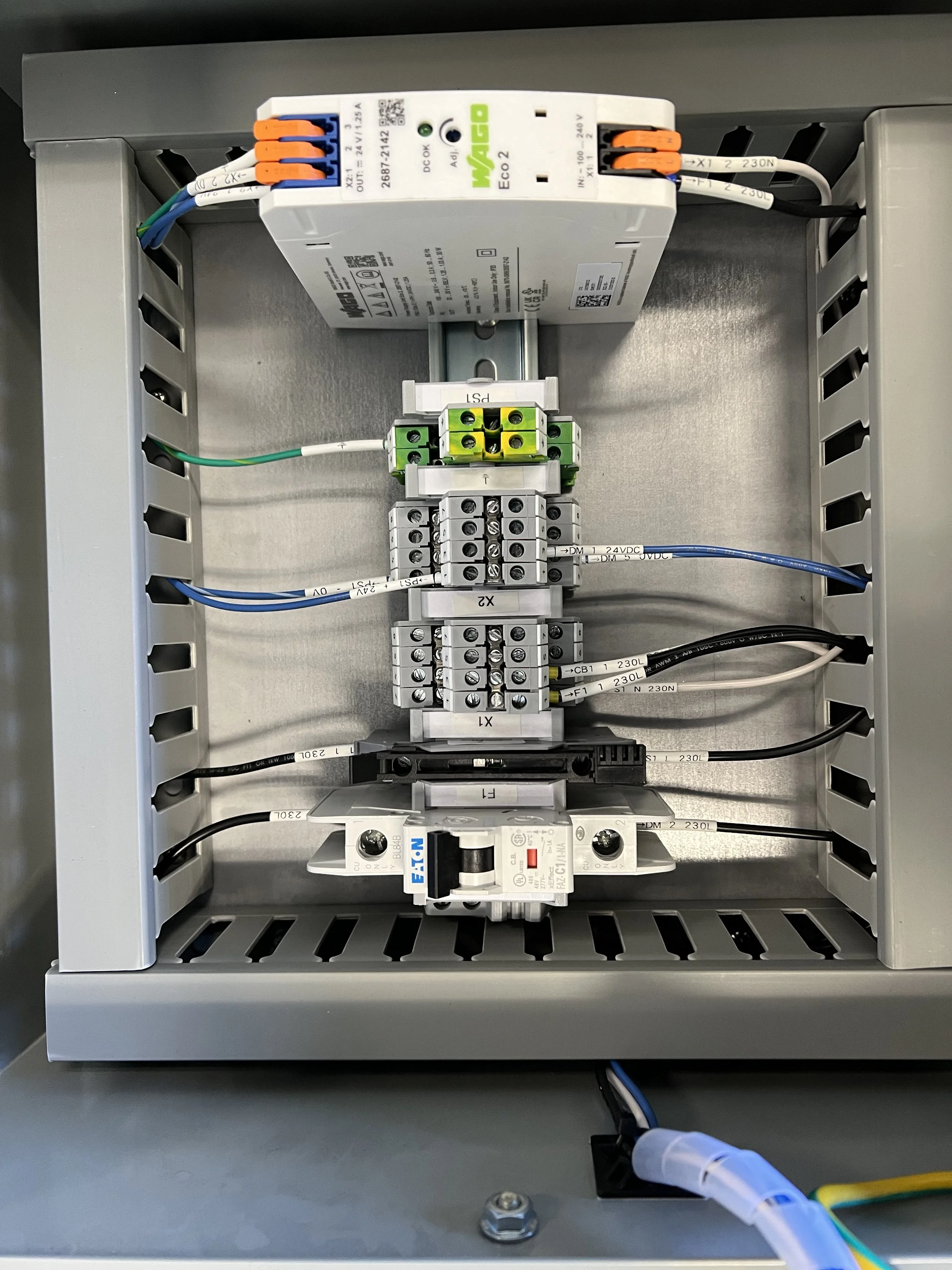 An electrical control panel with wiring and a power supply unit installed inside a metal enclosure.