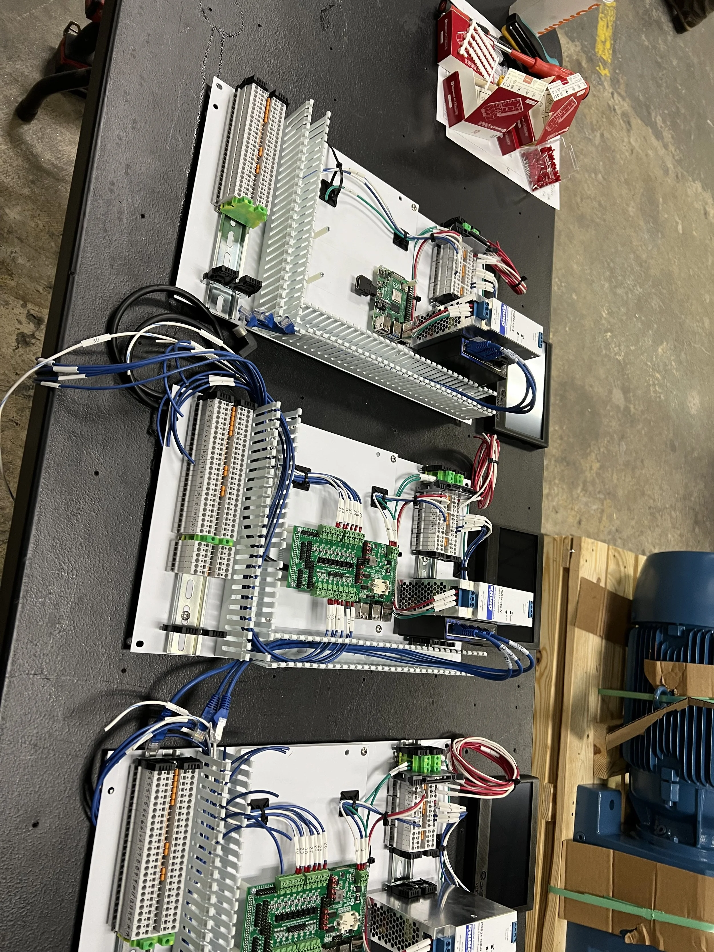 Close-up view of an electrical control panel with wiring and circuit components set up on a desk in an industrial environment.