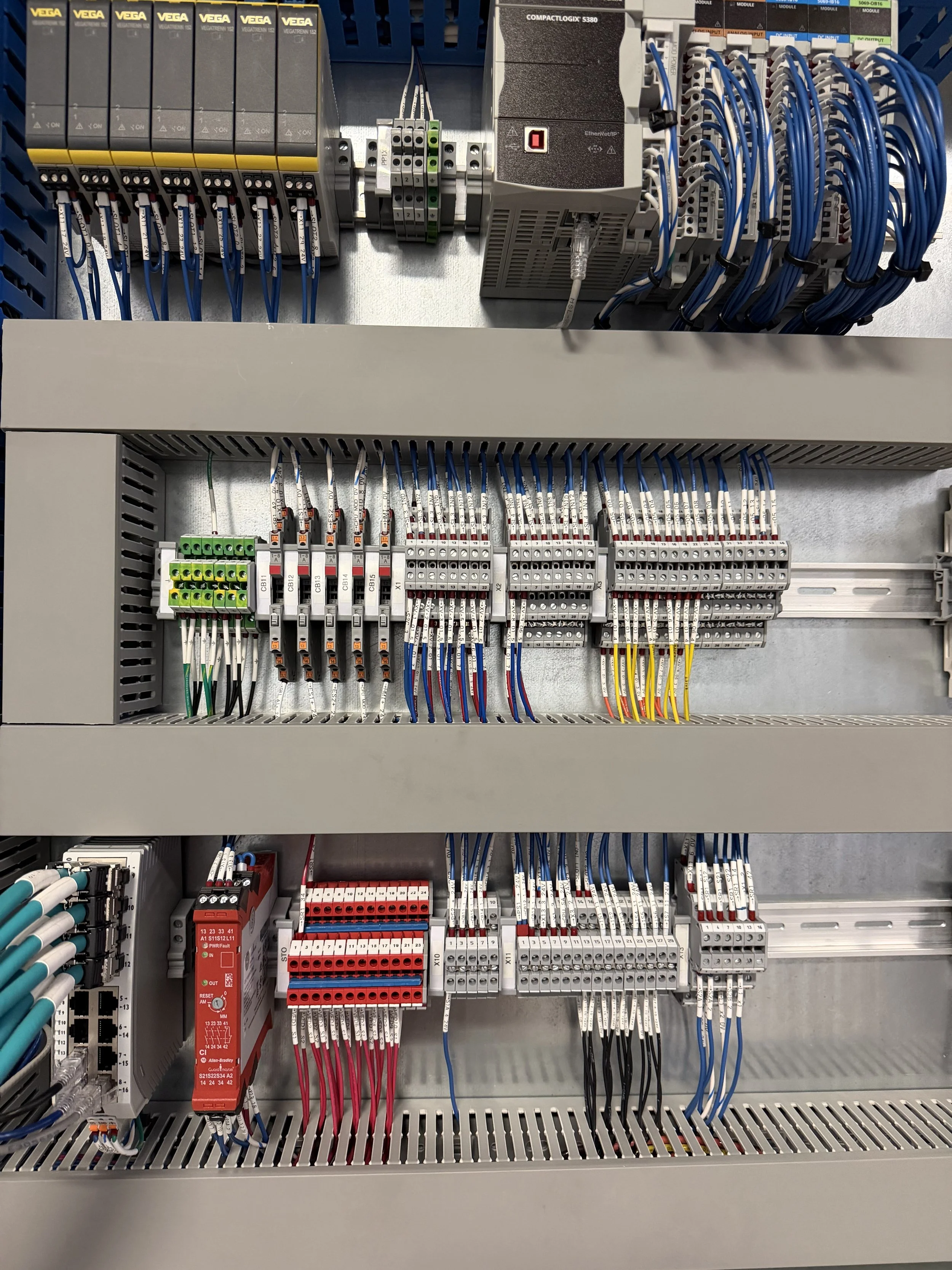 Electrical control panel with wiring, circuit breakers, and components organized inside a gray metal enclosure.