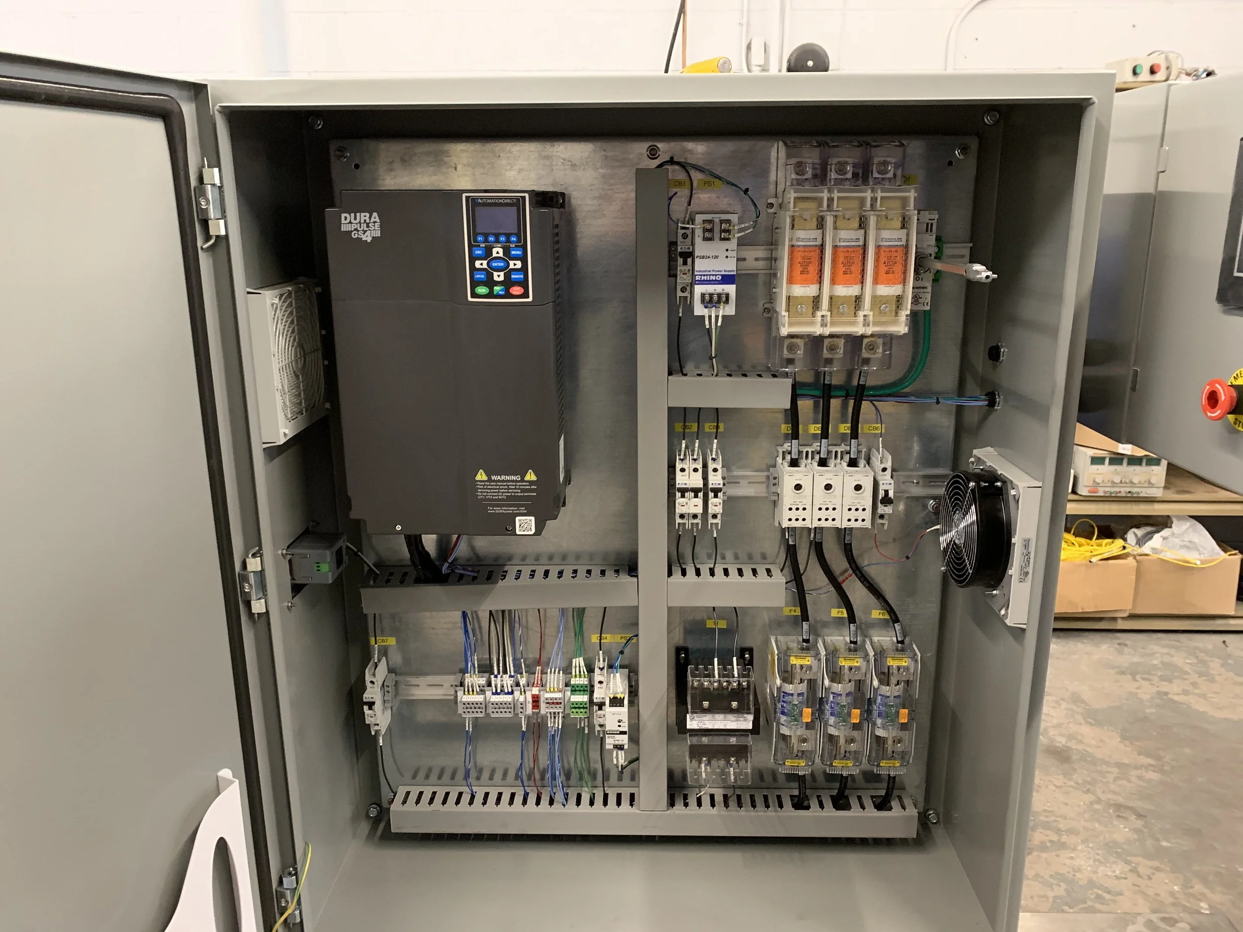 Open electrical control panel with various electrical components, wiring, and switches inside.