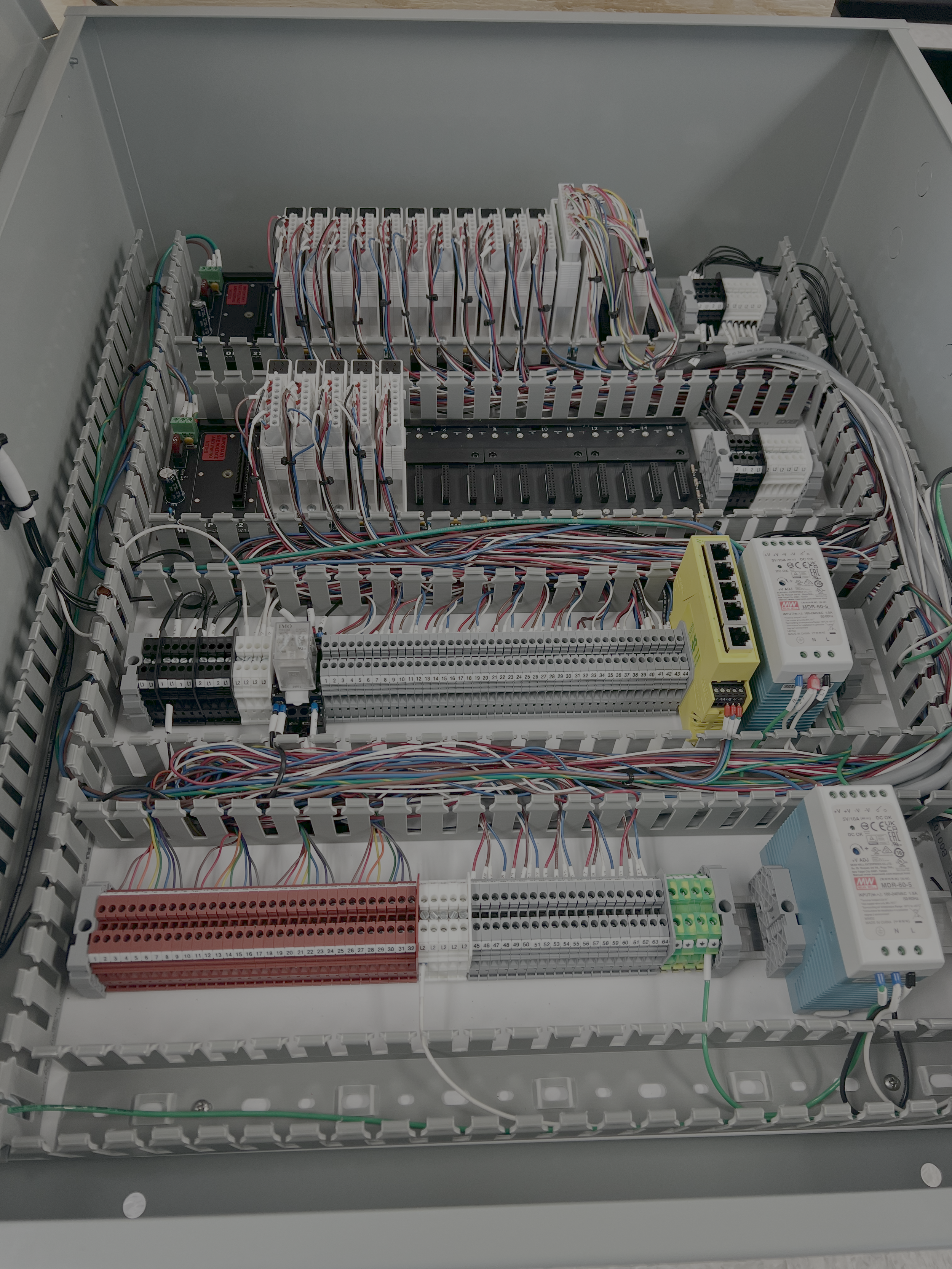 Electrical control panel with multiple wires, terminal blocks, relays, and circuit boards.