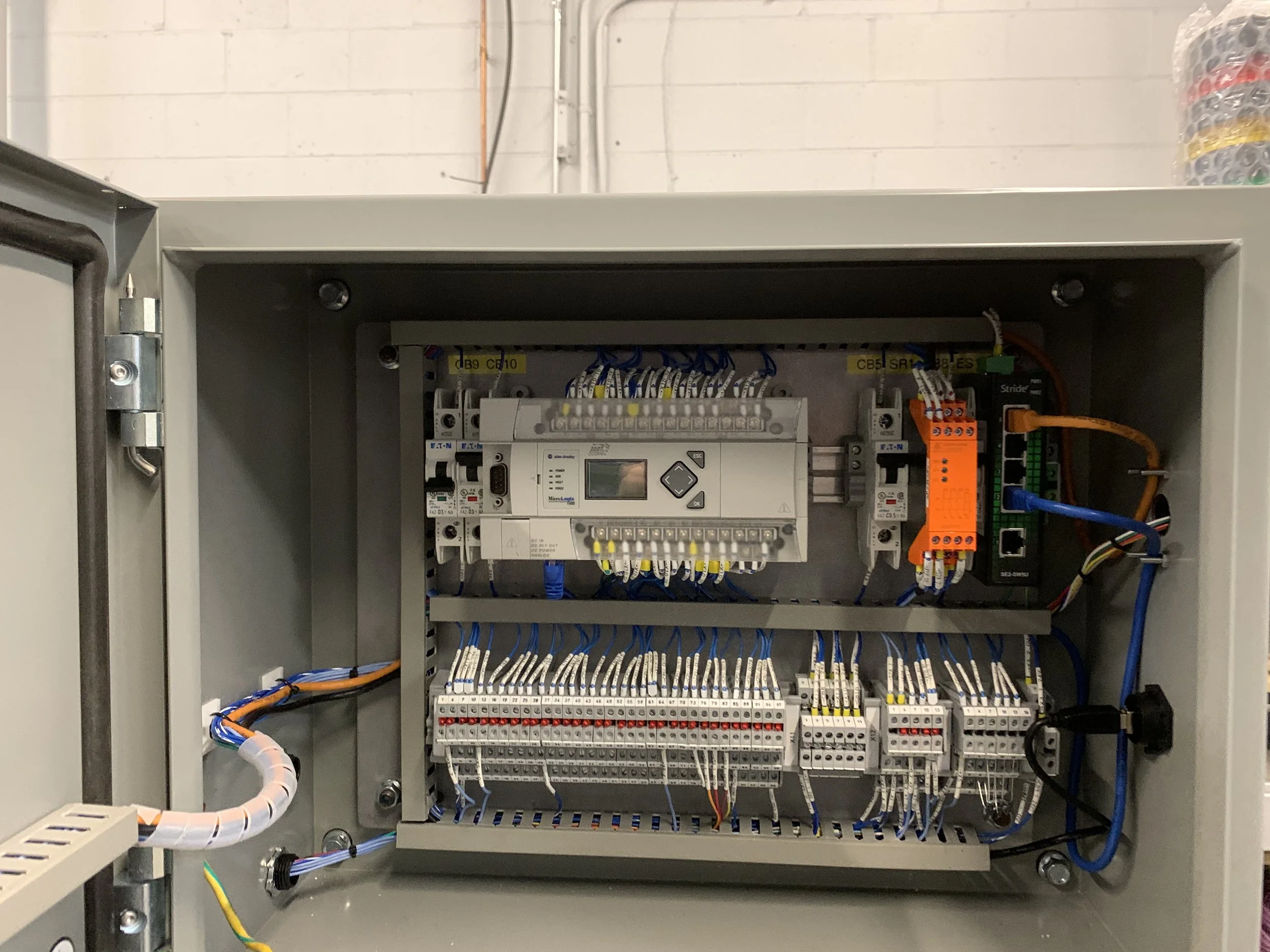 An electrical control panel with interior wiring, circuit breakers, and components inside a gray metal enclosure.