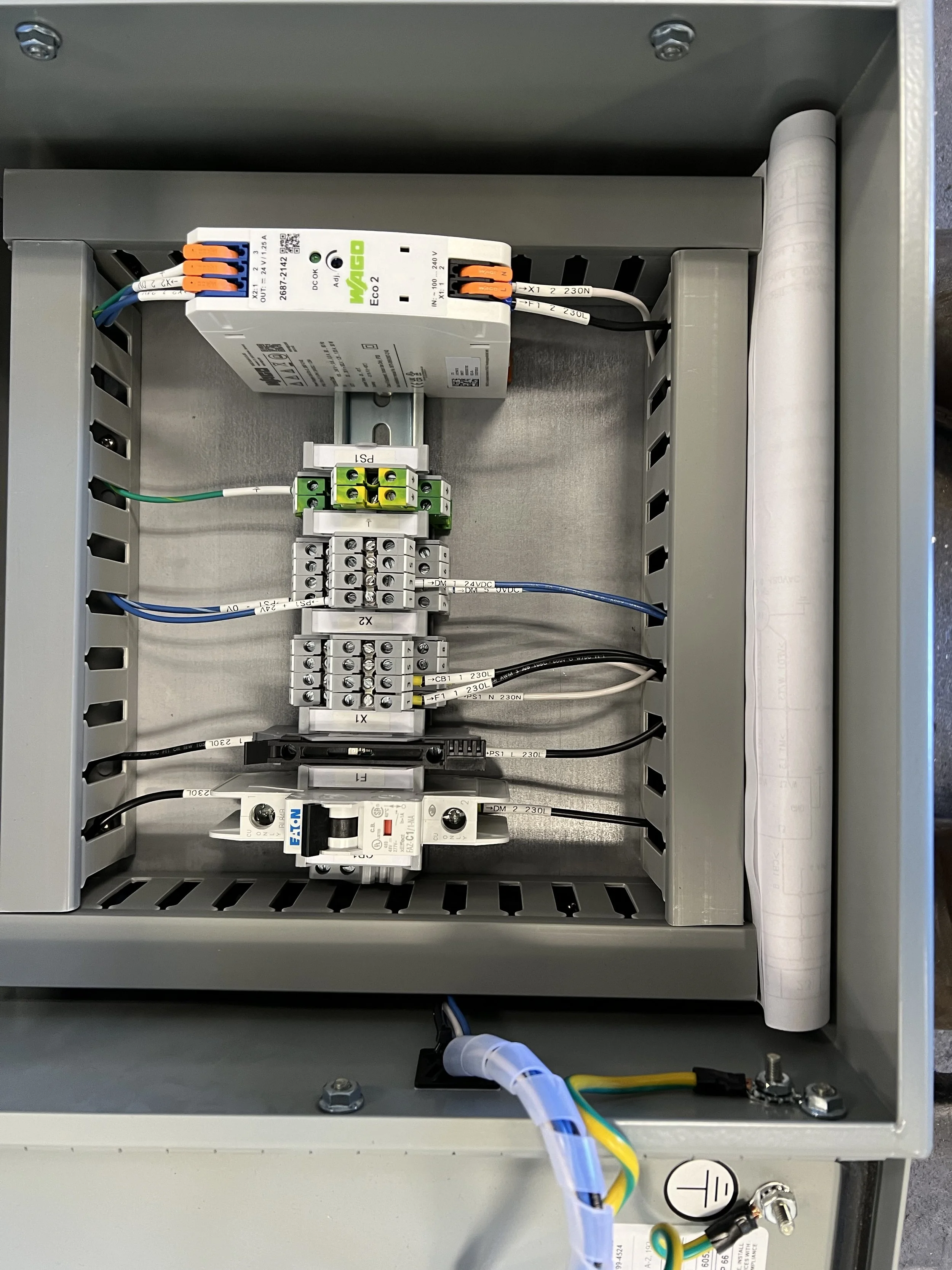 Interior view of an electrical control panel with various components, wires, and terminal blocks.
