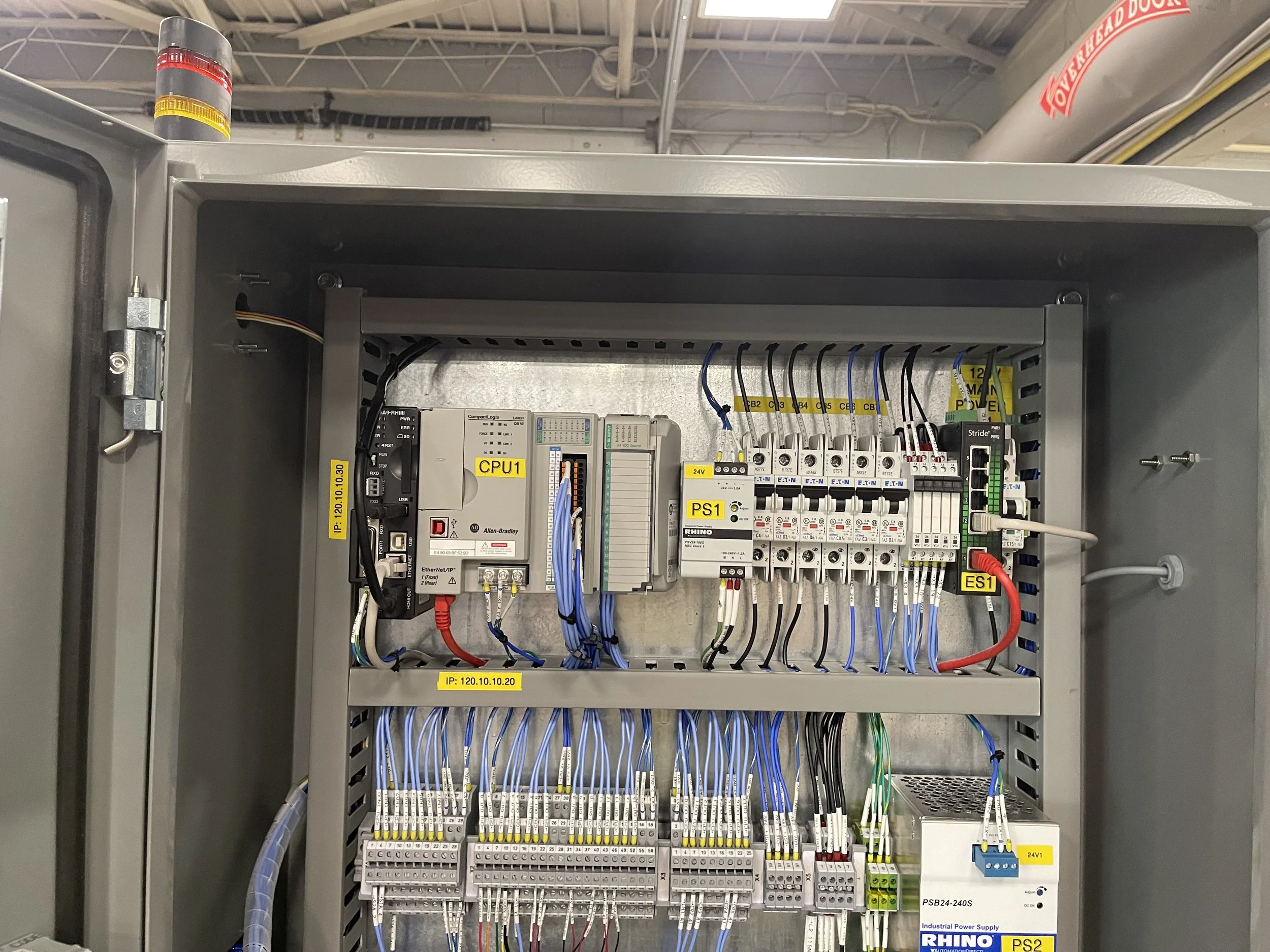 An open electrical control panel containing various wires, switches, and electronic modules, with labels such as CPU1, PS1, and IP: 120.10.10.20.