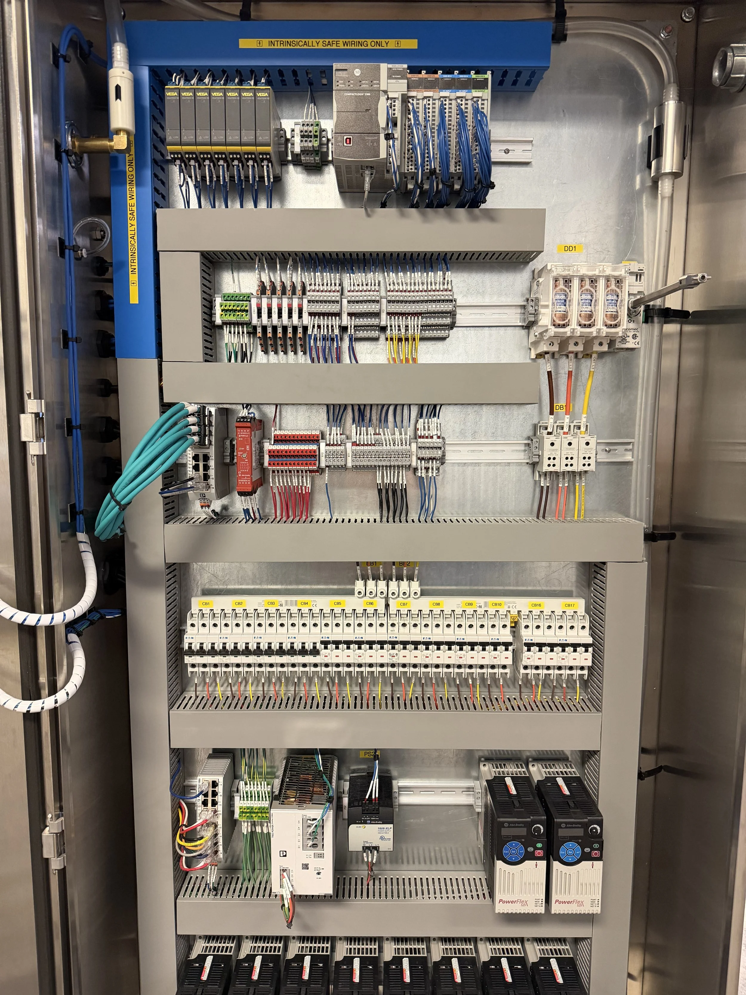 An electrical control panel with various wires, switches, and electronic components organized inside a metal cabinet.