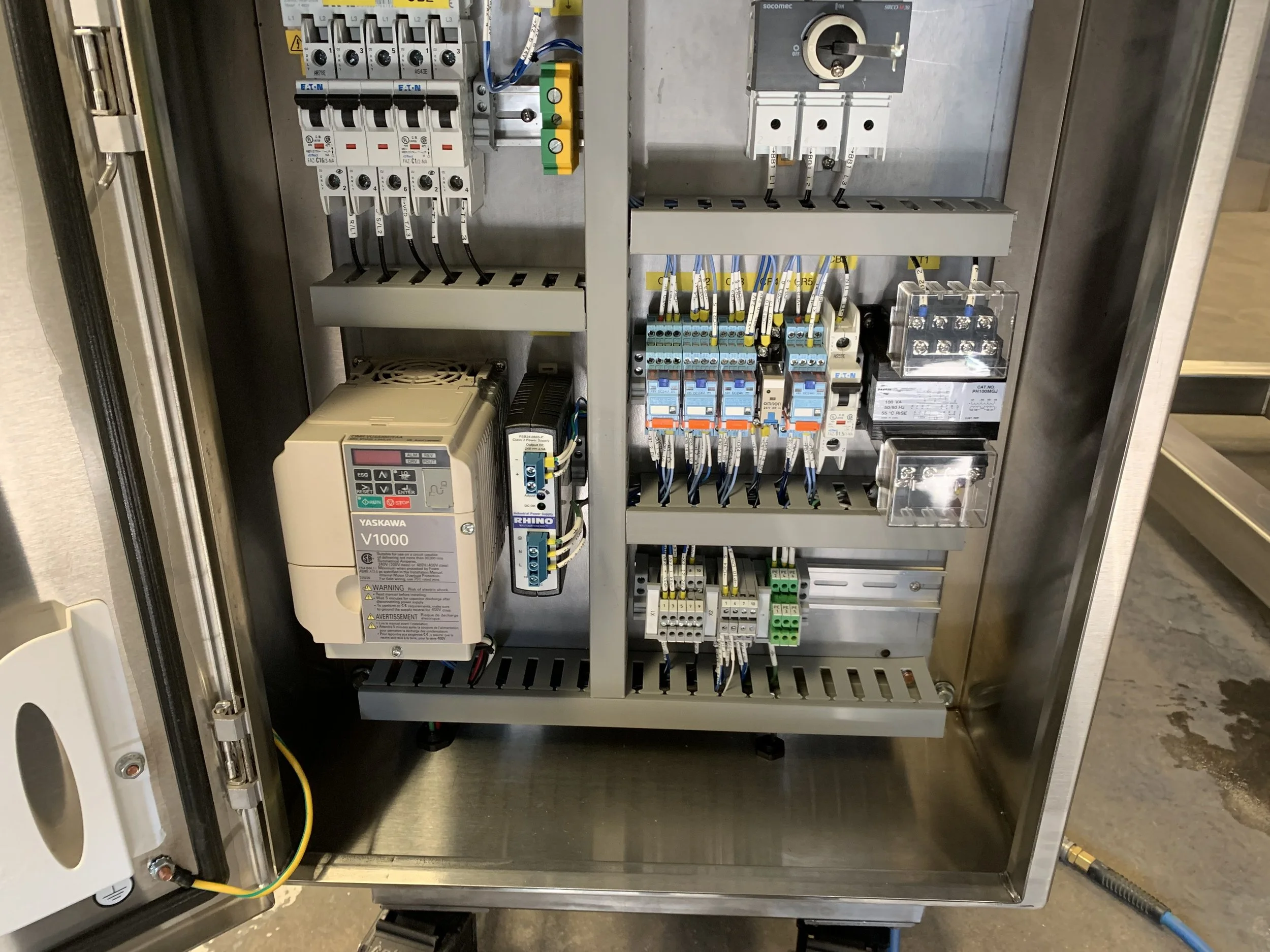 Electrical control panel with various circuit breakers, wiring, and components inside a metal enclosure.