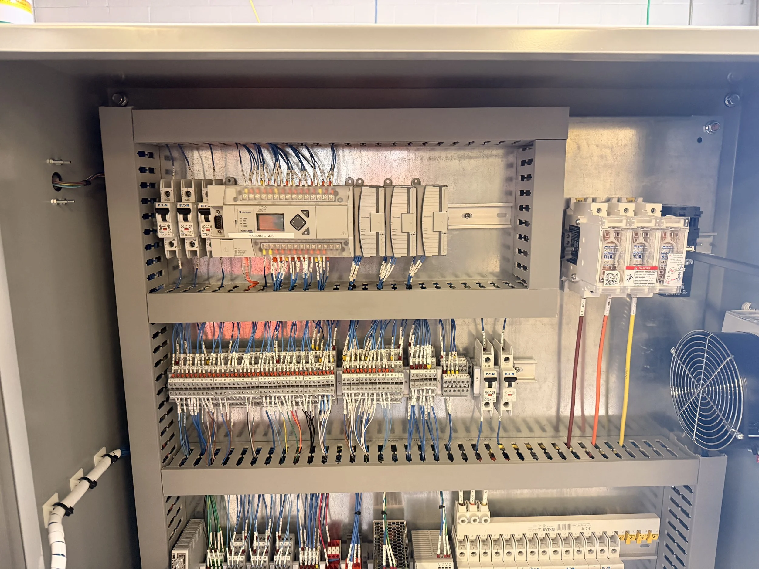 An open industrial electrical control panel with wiring and components inside.