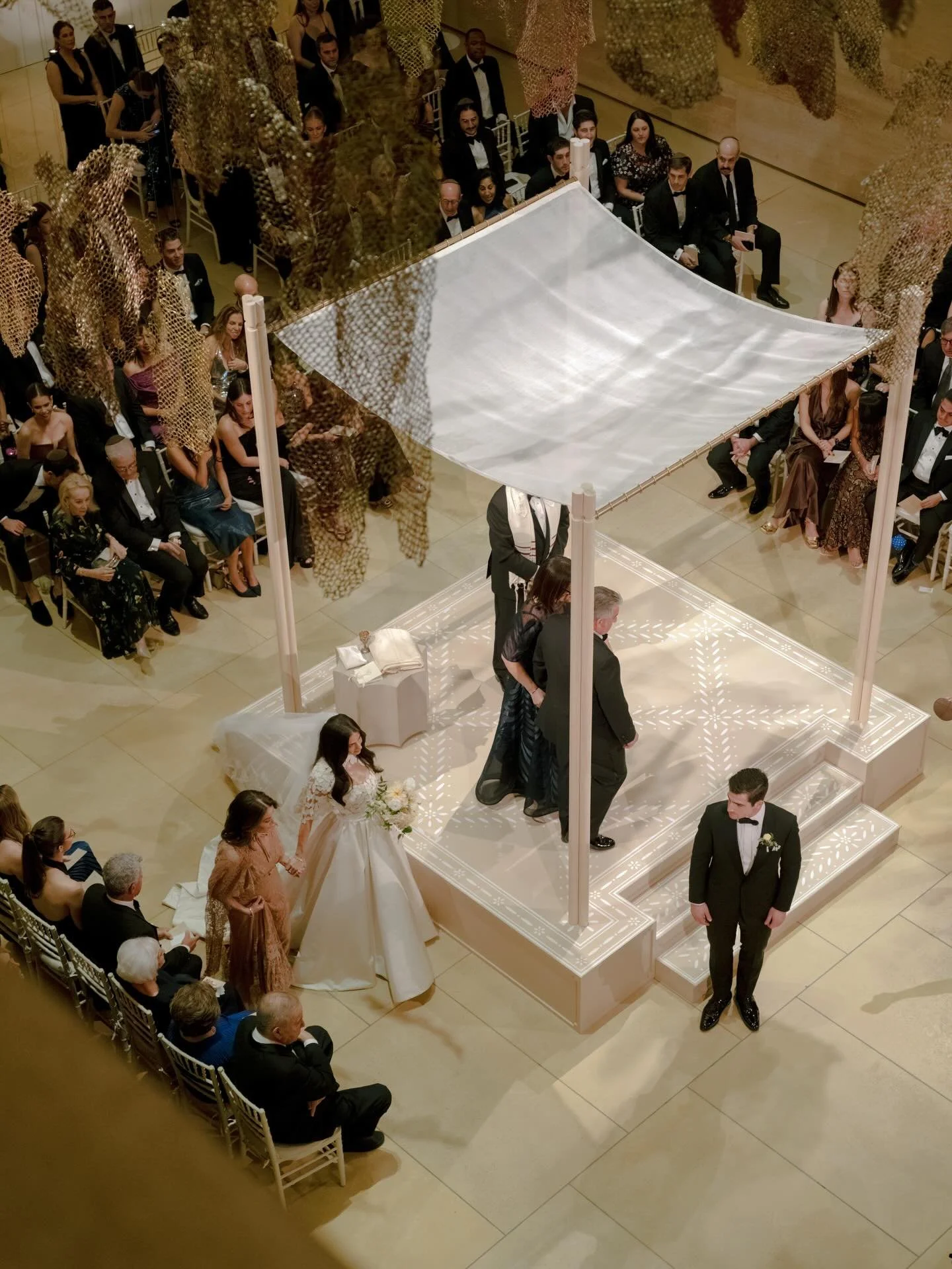 A ceremony as meaningful as it was beautiful. Jenna made a striking entrance, descending the stairs before approaching the chuppah alongside her mother.

@david_stark_design created a hand-painted structure in a tonal pattern, accented by three sculp