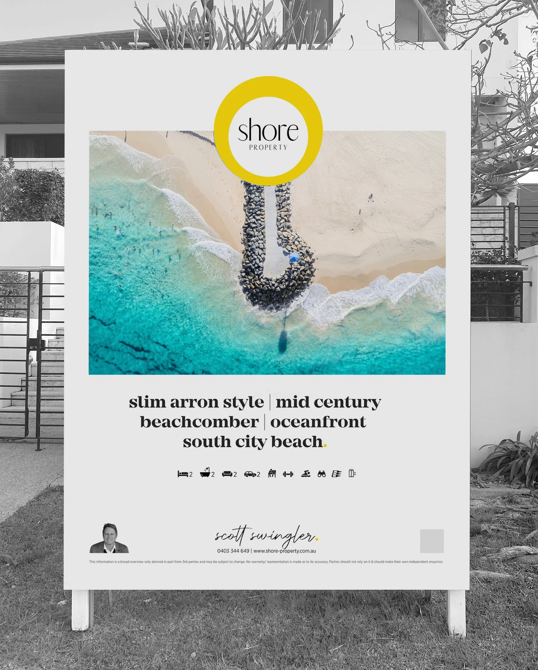 A real estate sign featuring an aerial photograph of a beachfront with clear blue water, sandy beach, and a rocky jetty. The sign displays the logo 'Shore Property' inside a yellow circle and includes property details for a mid-century beachcomber ho