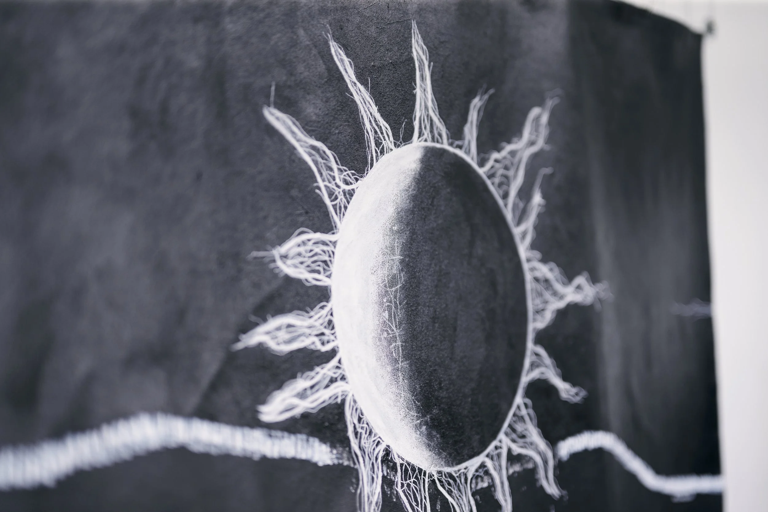 Black and white painting of a sun on an unstretched canvas 