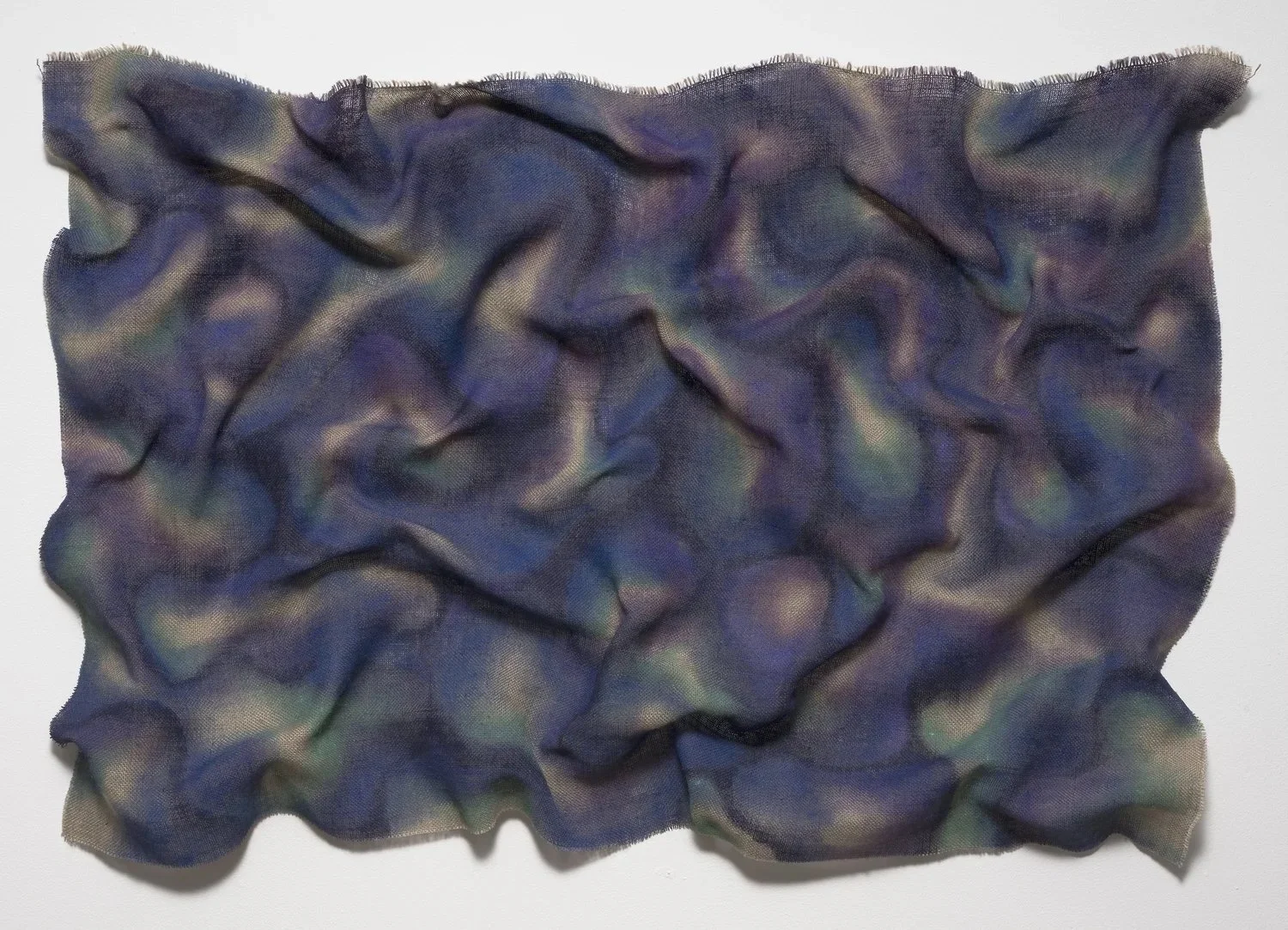 Purple, Blue, Green and Yellow fabric laid out in a wrinkled shape