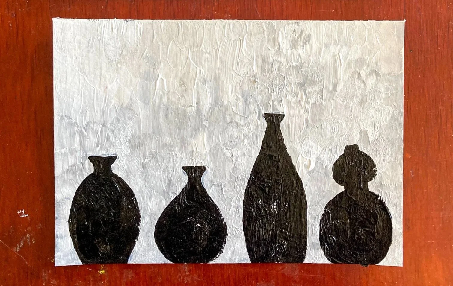 A painting of four silhouettes of ceramic vessels on a white background.