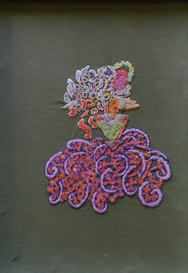 An embroidered creature with sharp teeth and tentacles multicolour on a green background 