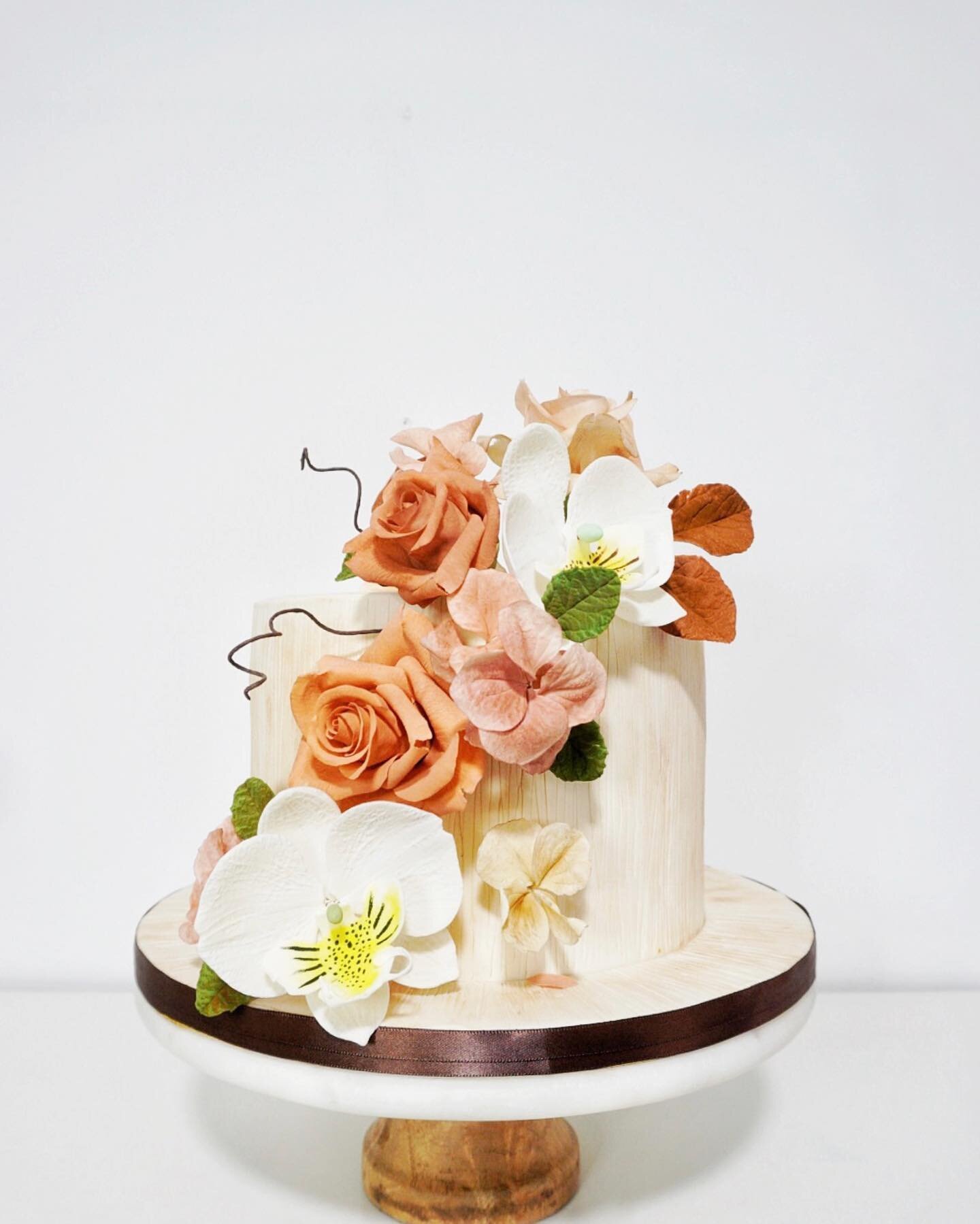 Inspired by autumn colours, this cake shows off a cascading arrangement of sugar flowers that never wilt and last a long time. Store your sugar flowers as your wedding keepsake! 🤎 #CakeVowWeddings