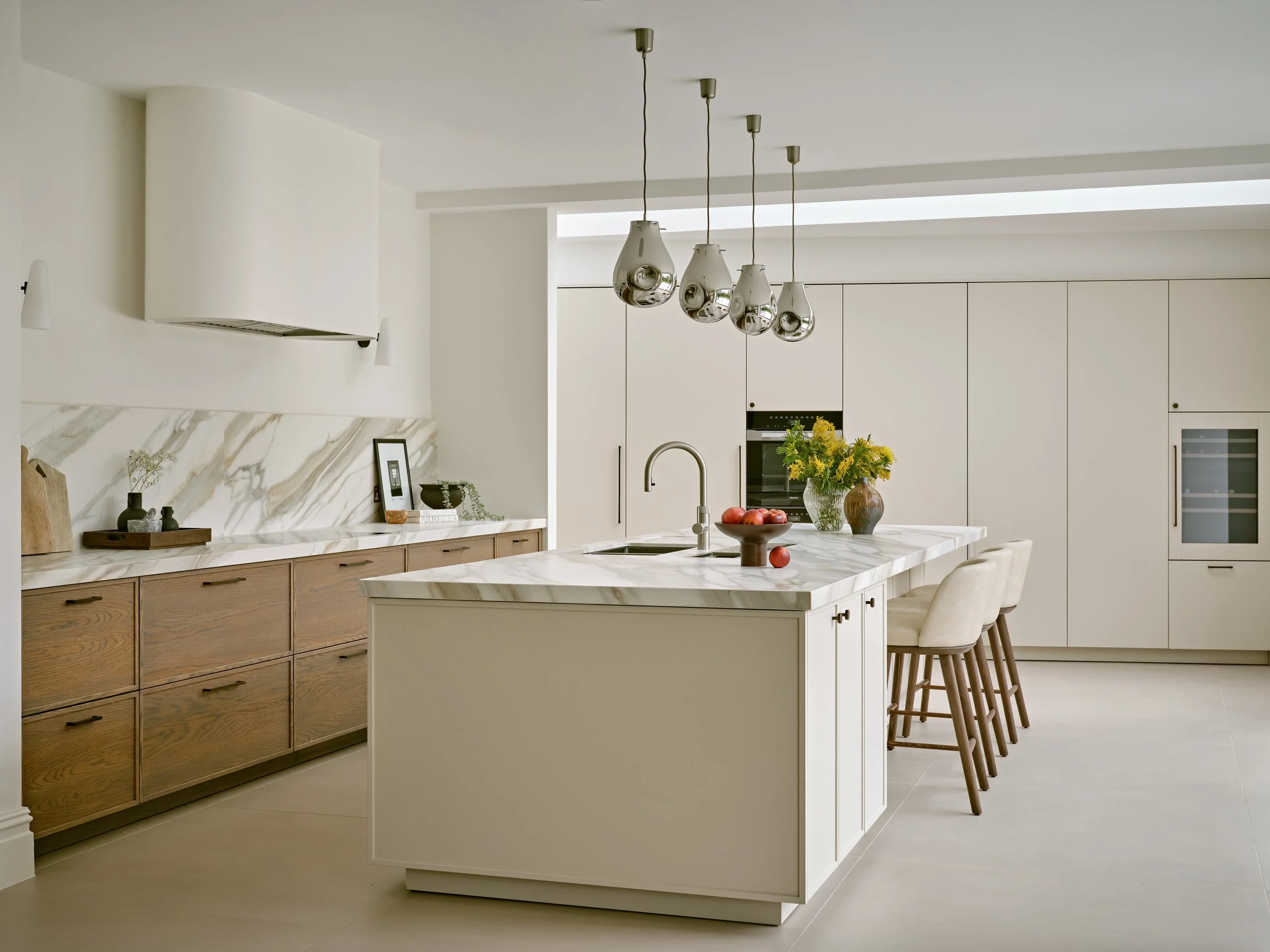 Modern white and wood kitchen with Sapienstone island, pendant lighting, and minimalist cabinetry in a bright, contemporary interior.