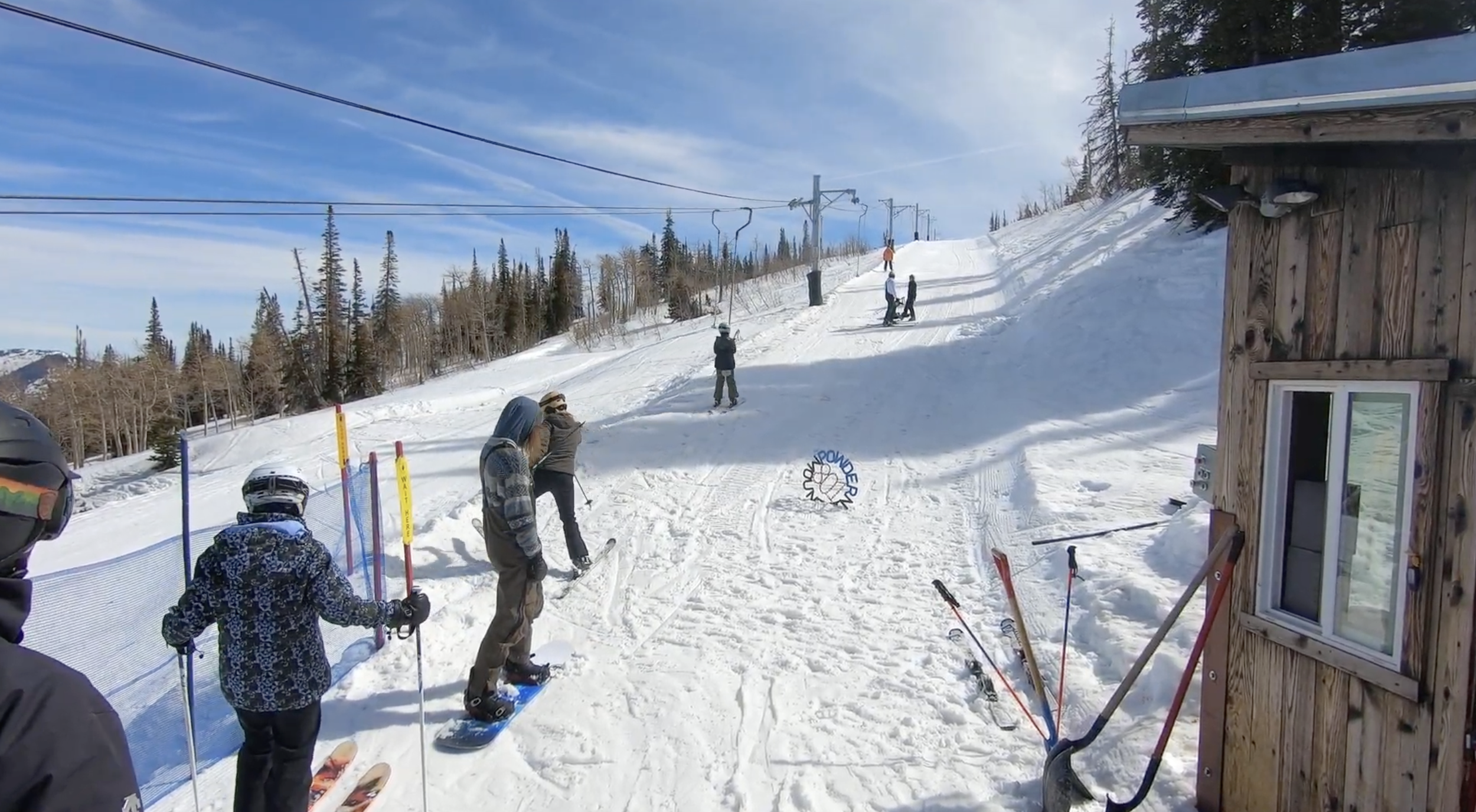 Skiers and snowboarders board a poma lift on a sunny day at Powder Mountain ski resort, Utah
