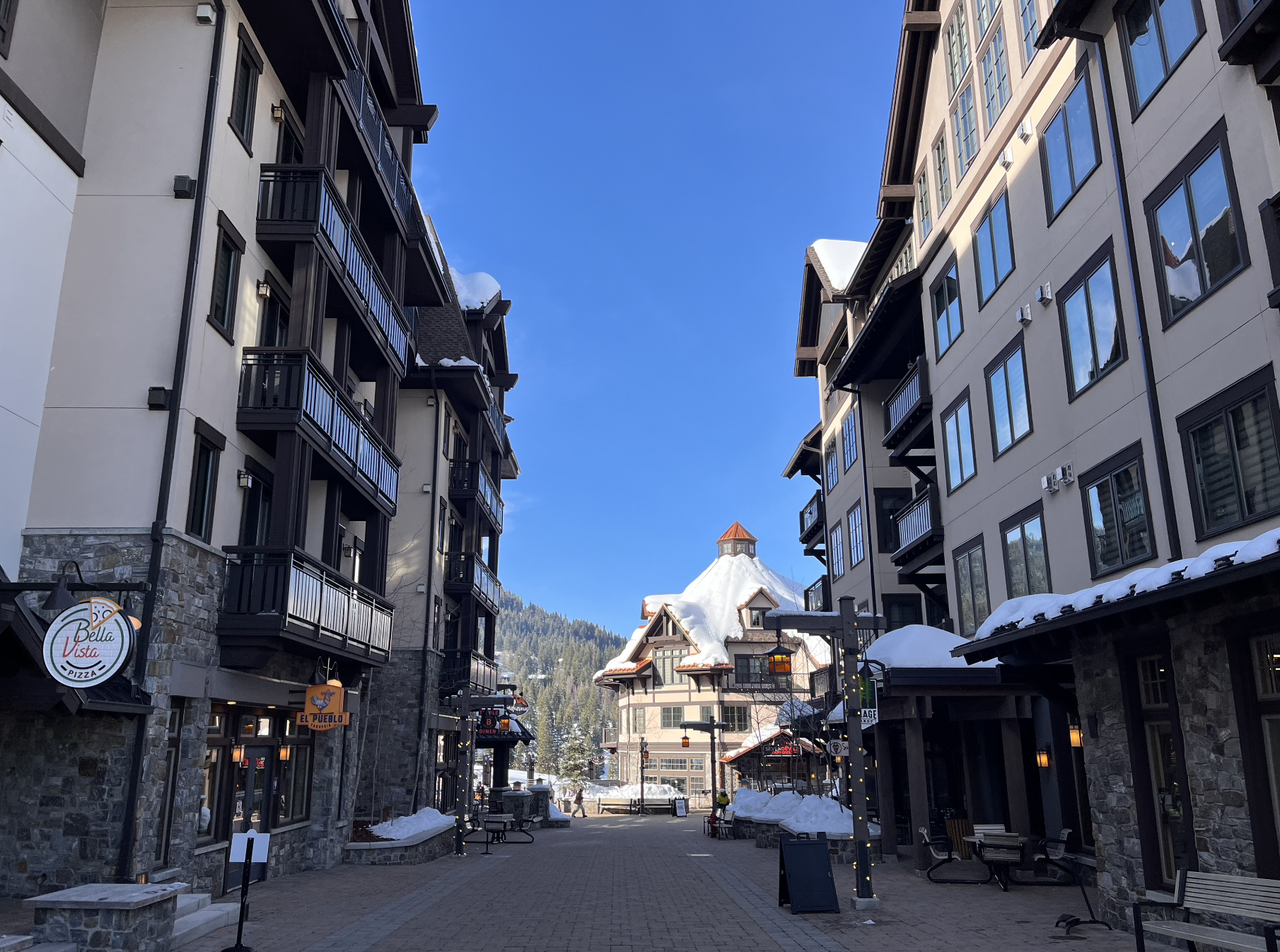 Idyllic and quiet street in a snowy mountain village between condos on a clear day at Tamarack ski resort, Idaho