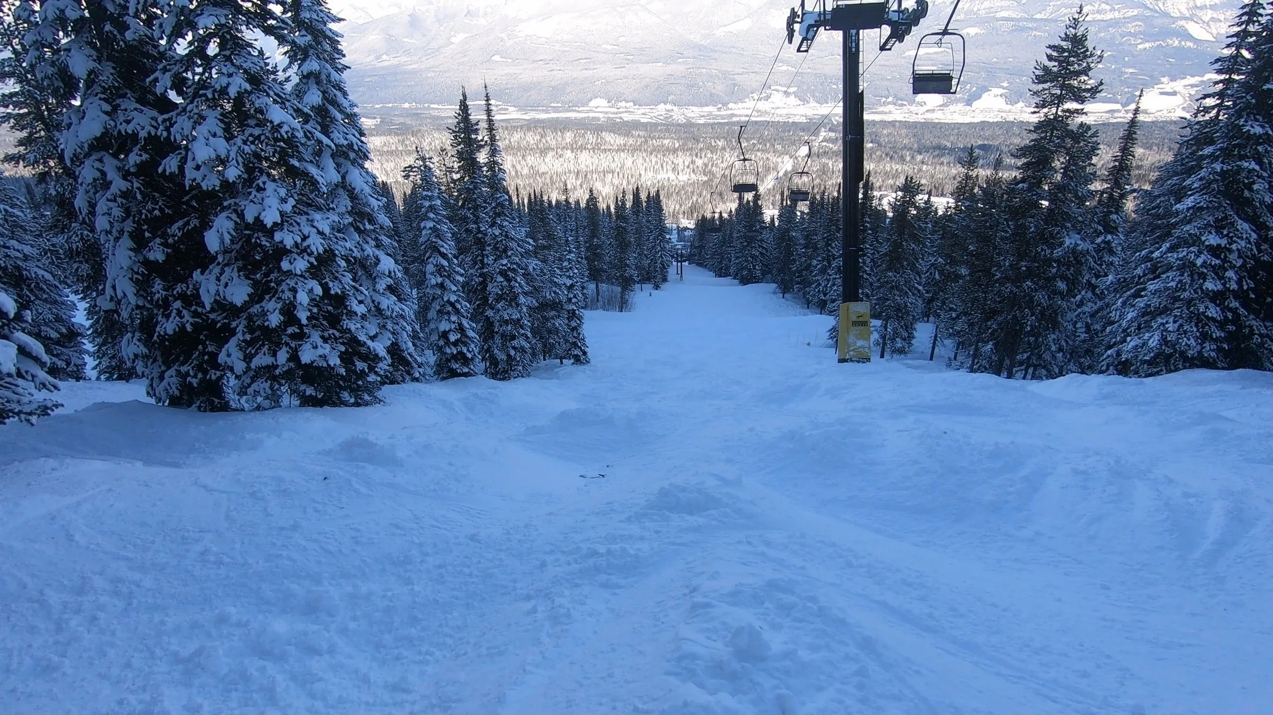 Kicking Horse's snowy steep terrain with the Pioneer double chairlift in the background.