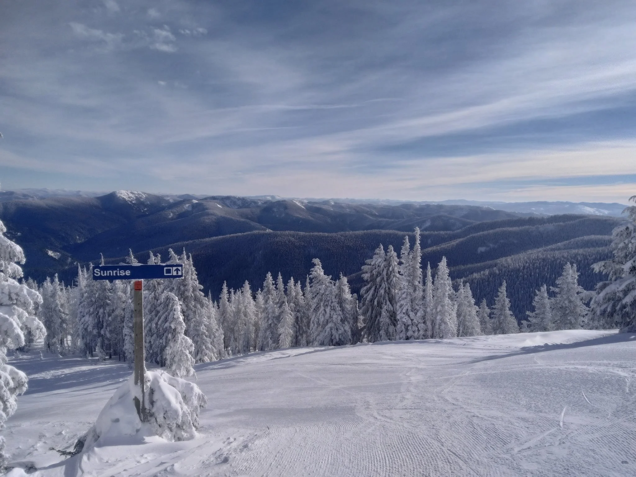 Blue square Sunrise trail sign above a groomed intermediate run at Silver Mountain