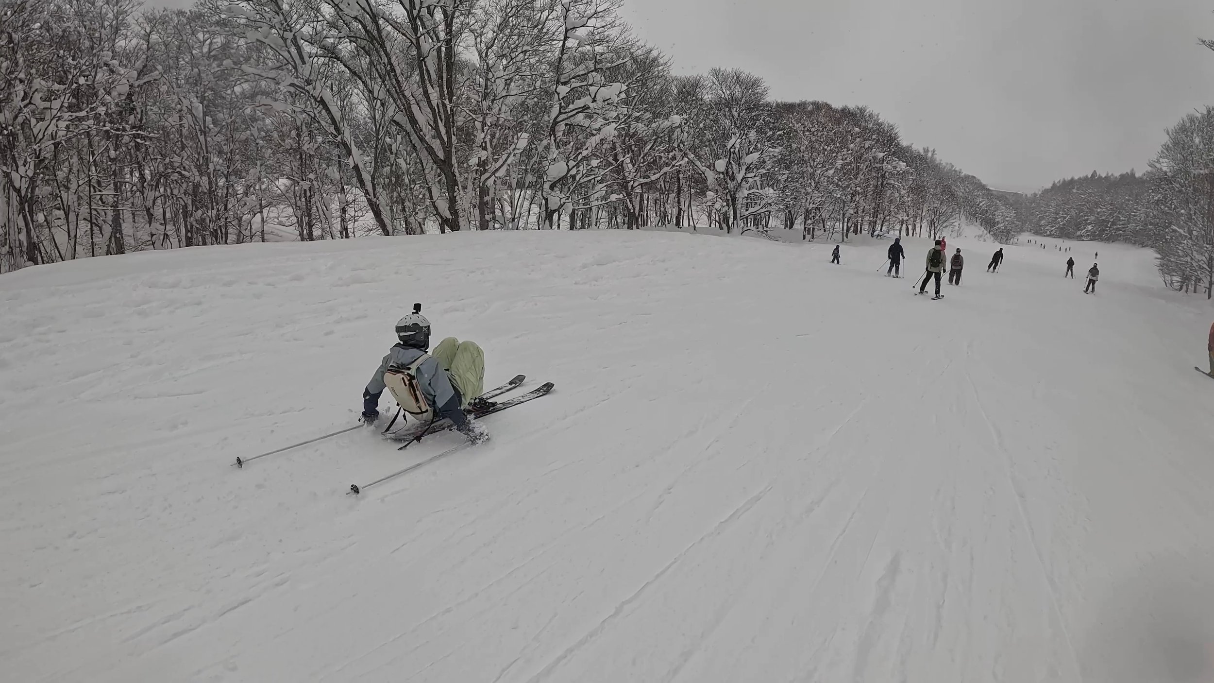 A skier crouching on a busy ski slope.